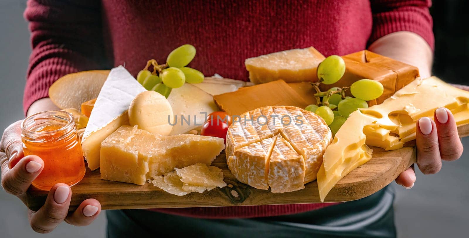 Girl holding different kinds of cheese and honey on wooden table in hands closeup. Woman with organic parmesan and brie set french delicatessen