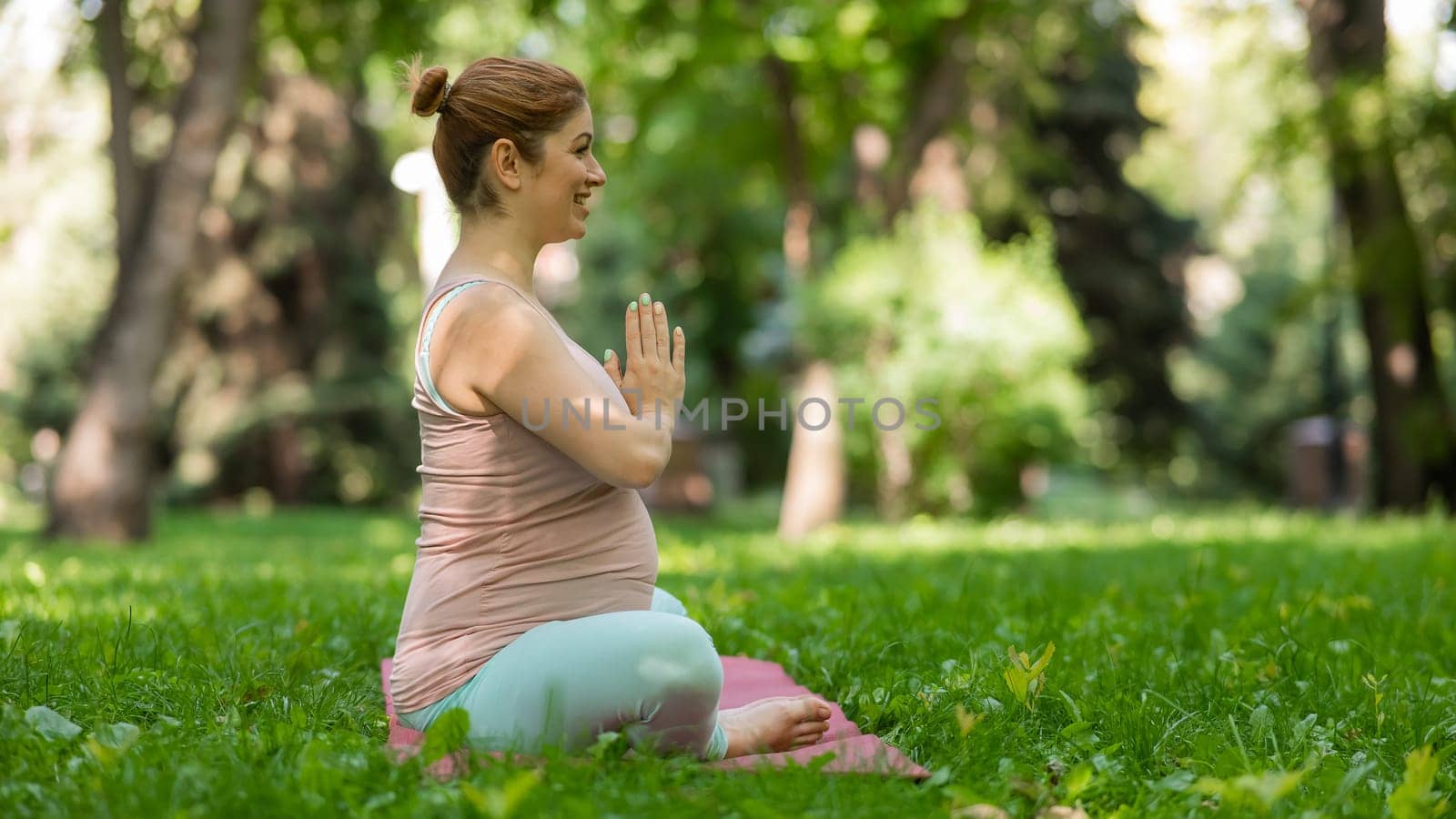 Prenatal yoga. Caucasian pregnant woman doing butterfly pose in the park