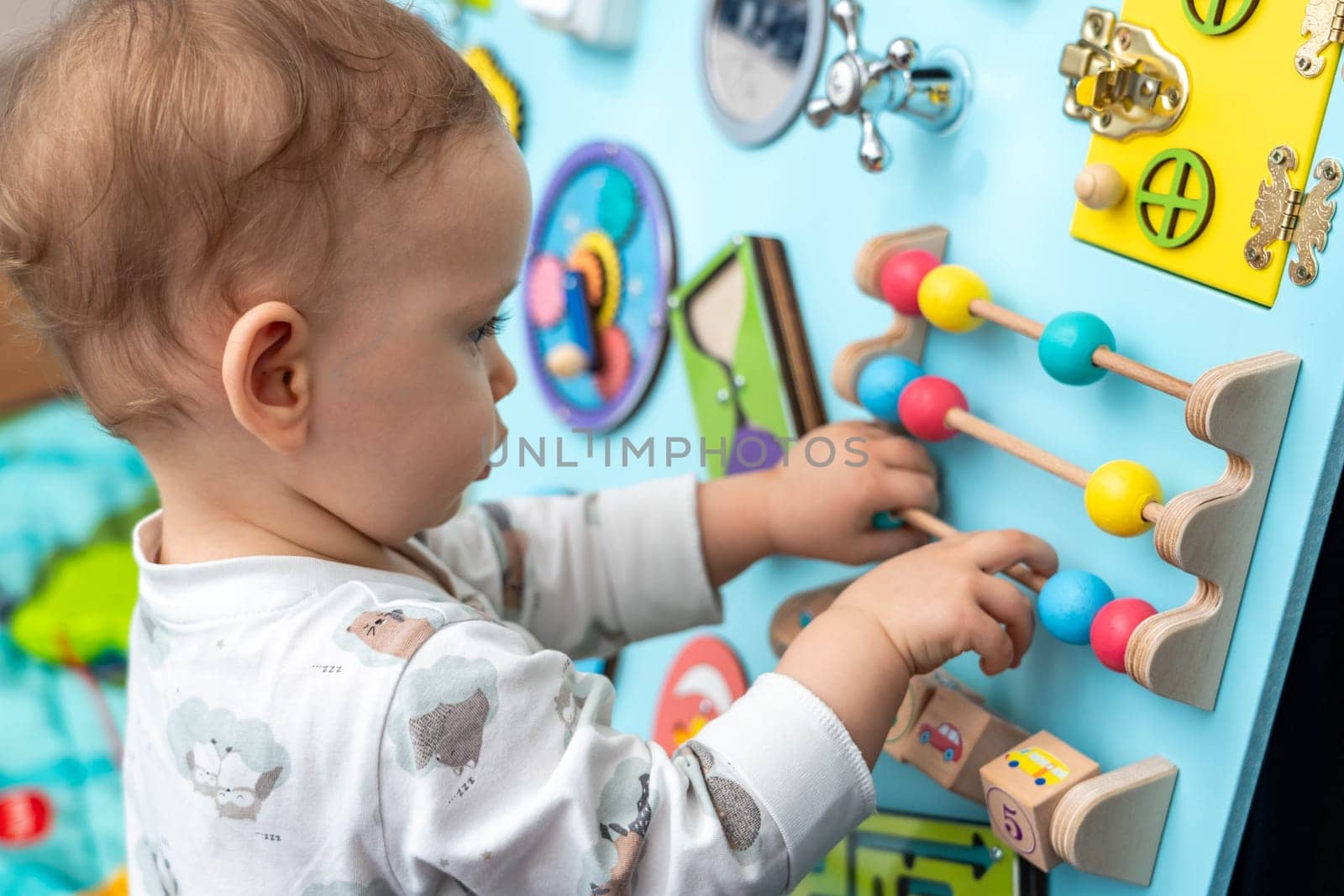 A child enthusiastically plays with toy abacus on a busy board.