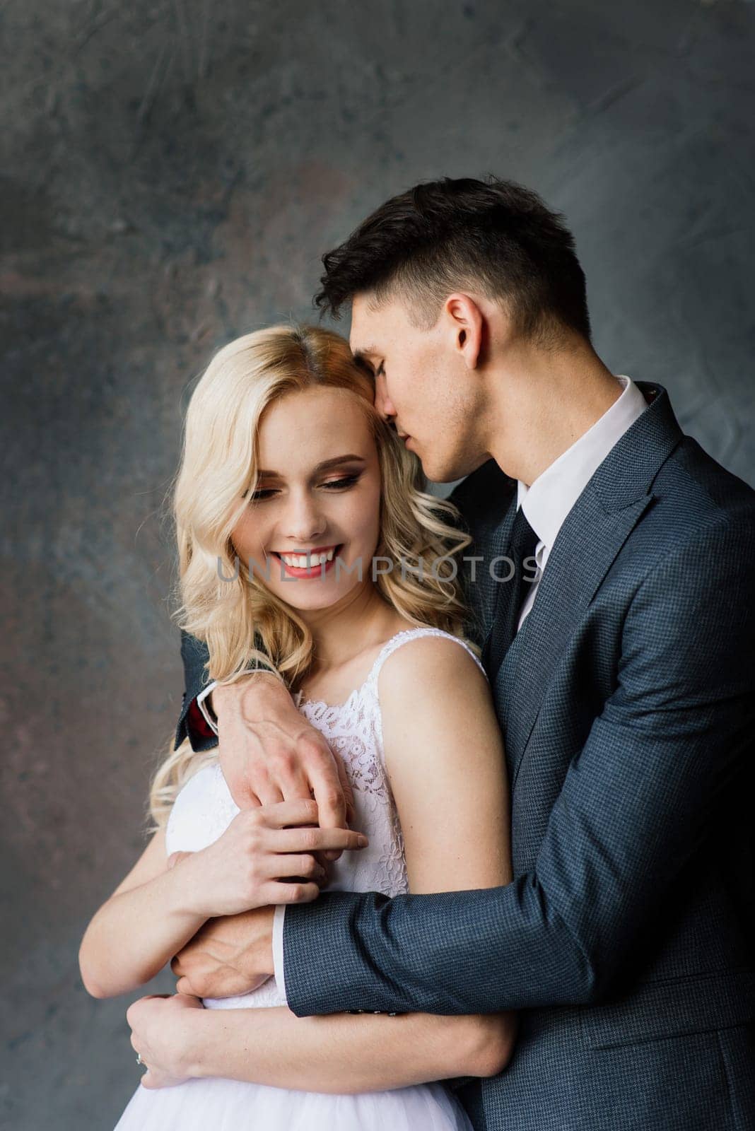 Cute wedding couple in the interior of a classic studio decorated. They kiss and hug each other. by Zelenin
