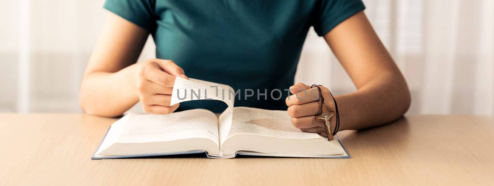 Female believer reads holy bible faithfully while holding cross at light wooden church. Concept of hope, religion, faith, believe, christianity, catholic and god blessing. Front view. Burgeoning.