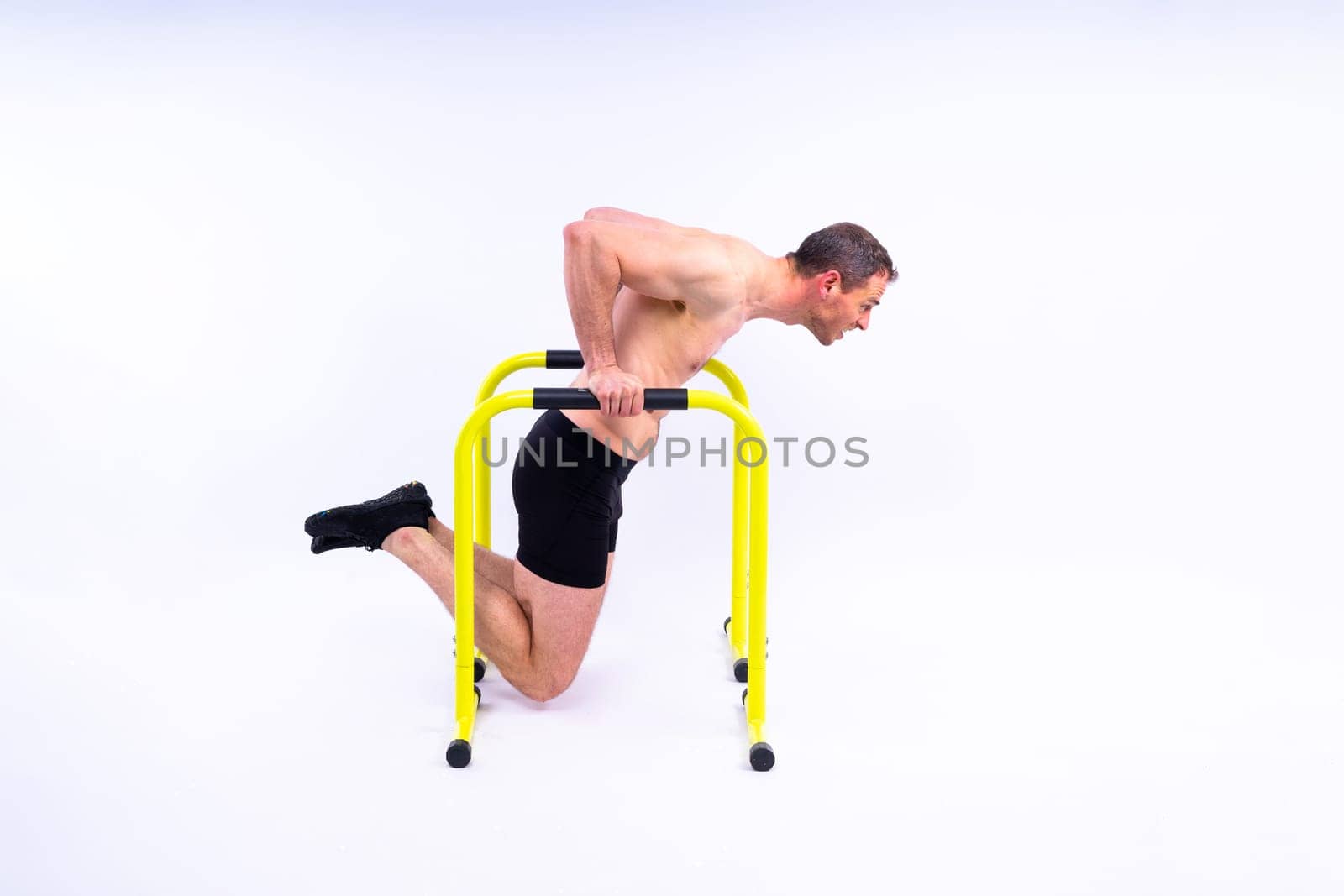 Male gymnast performing handstand on a parallel bars, studio shot