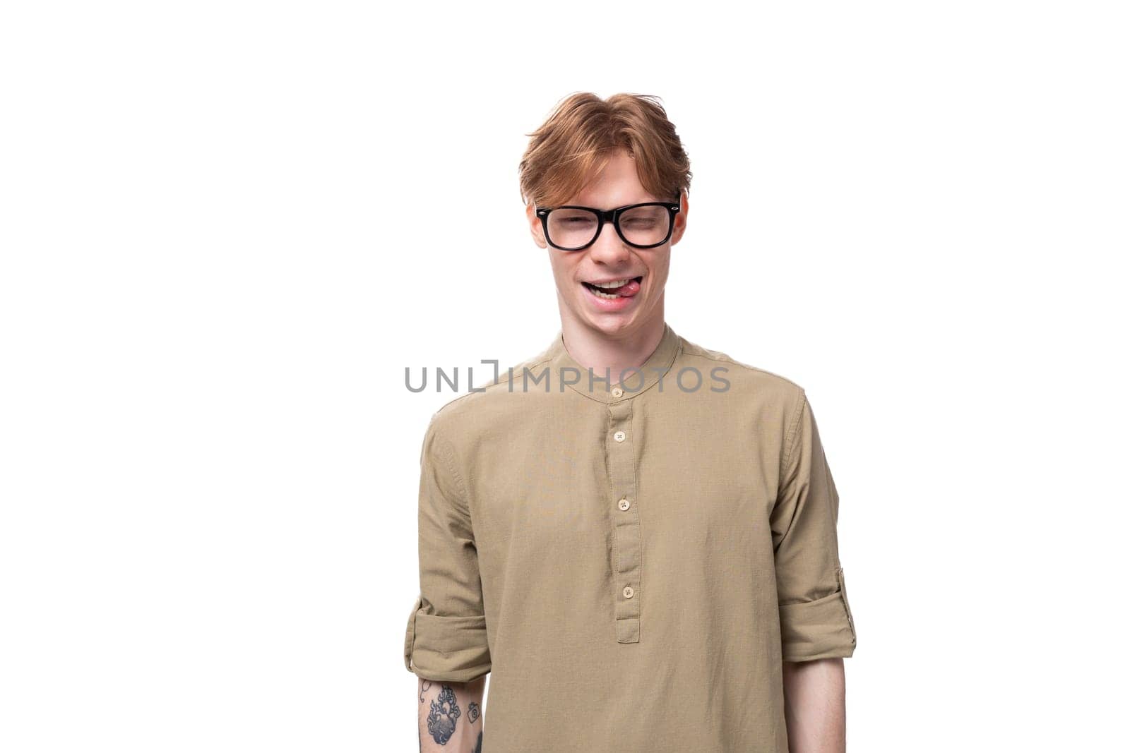 close-up portrait of a stylish european guy with red hair dressed in a fashionable brown shirt and trousers on a white background. people lifestyle concept.