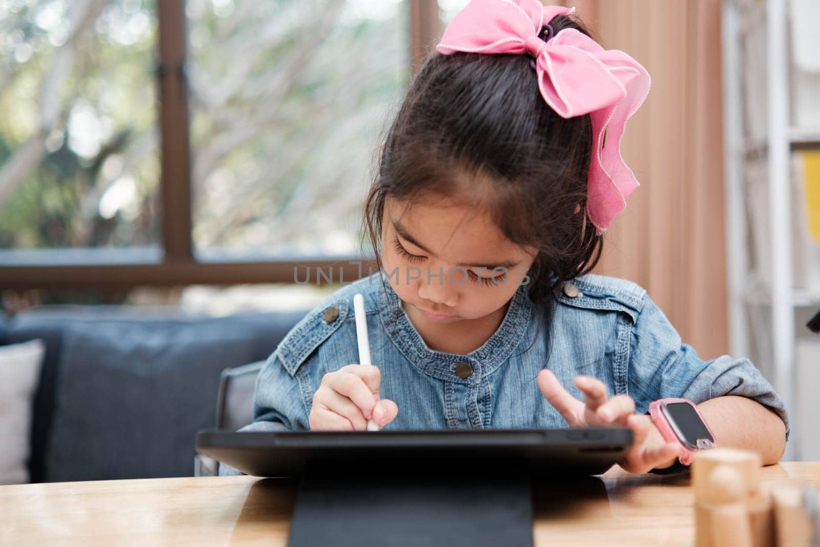 A primary school girl focuses on operating a robotic arm with a remote control, demonstrating STEM education in action.