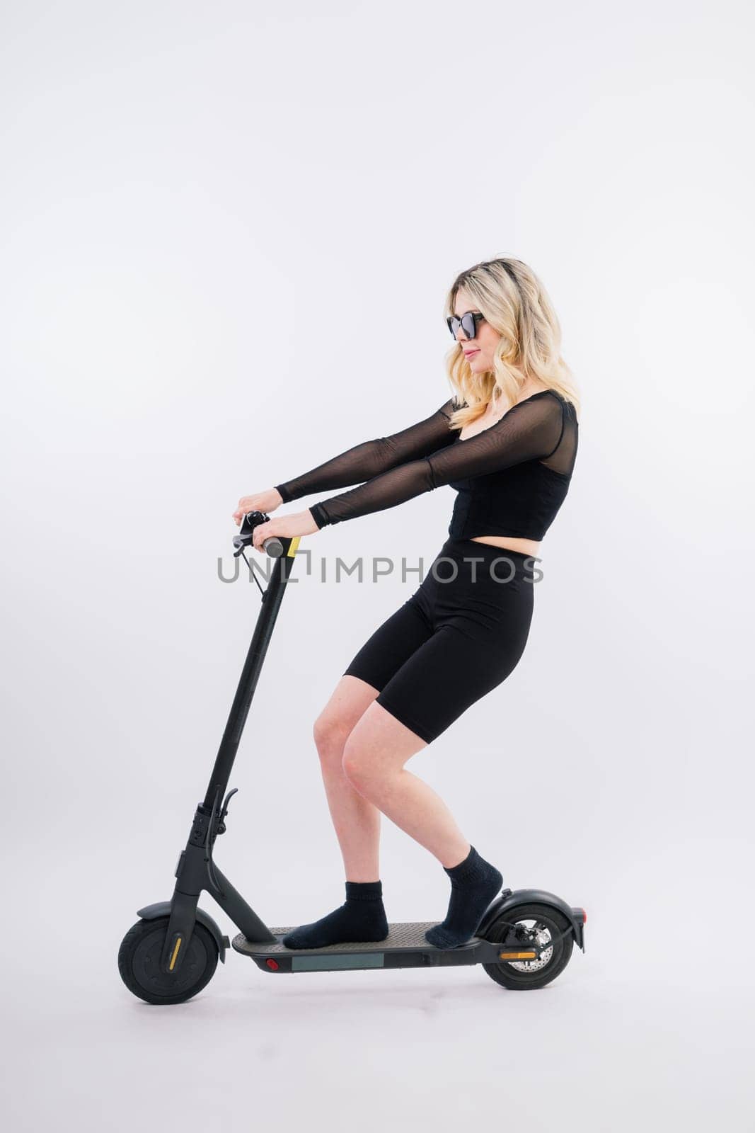 Happy young woman wear glasses riding electric scooter on background studio People lifestyle concept by Zelenin