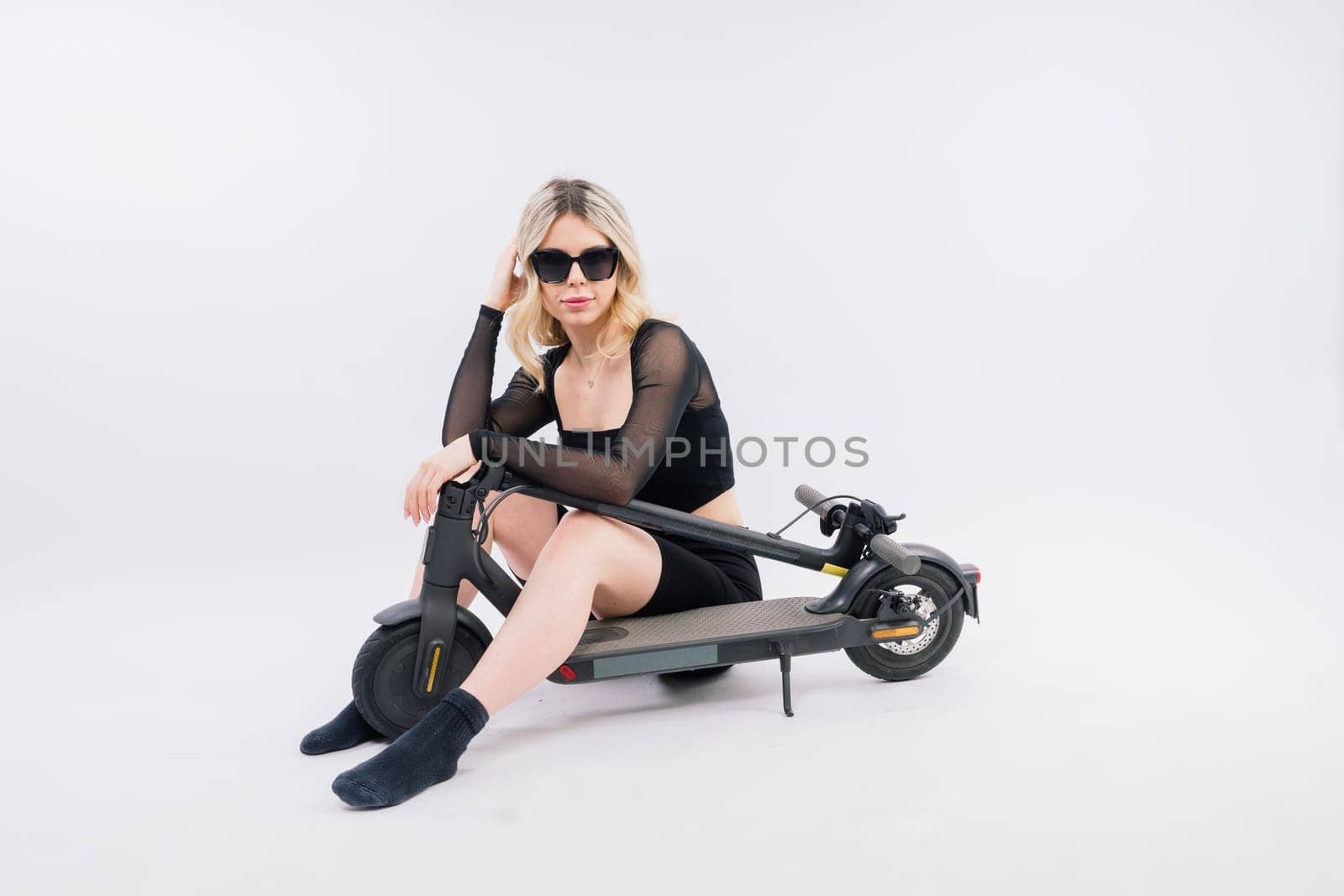 Happy young woman wear glasses riding electric scooter on background studio People lifestyle concept by Zelenin