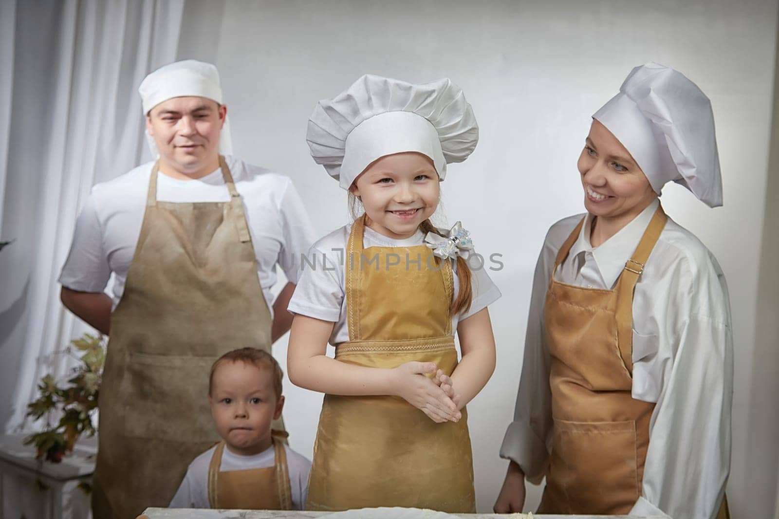 Cute oriental family with mother, father, daughter, son cooking in kitchen on Ramadan, Kurban-Bairam, Eid al-Adha. Funny family at photo shoot. Easter by keleny