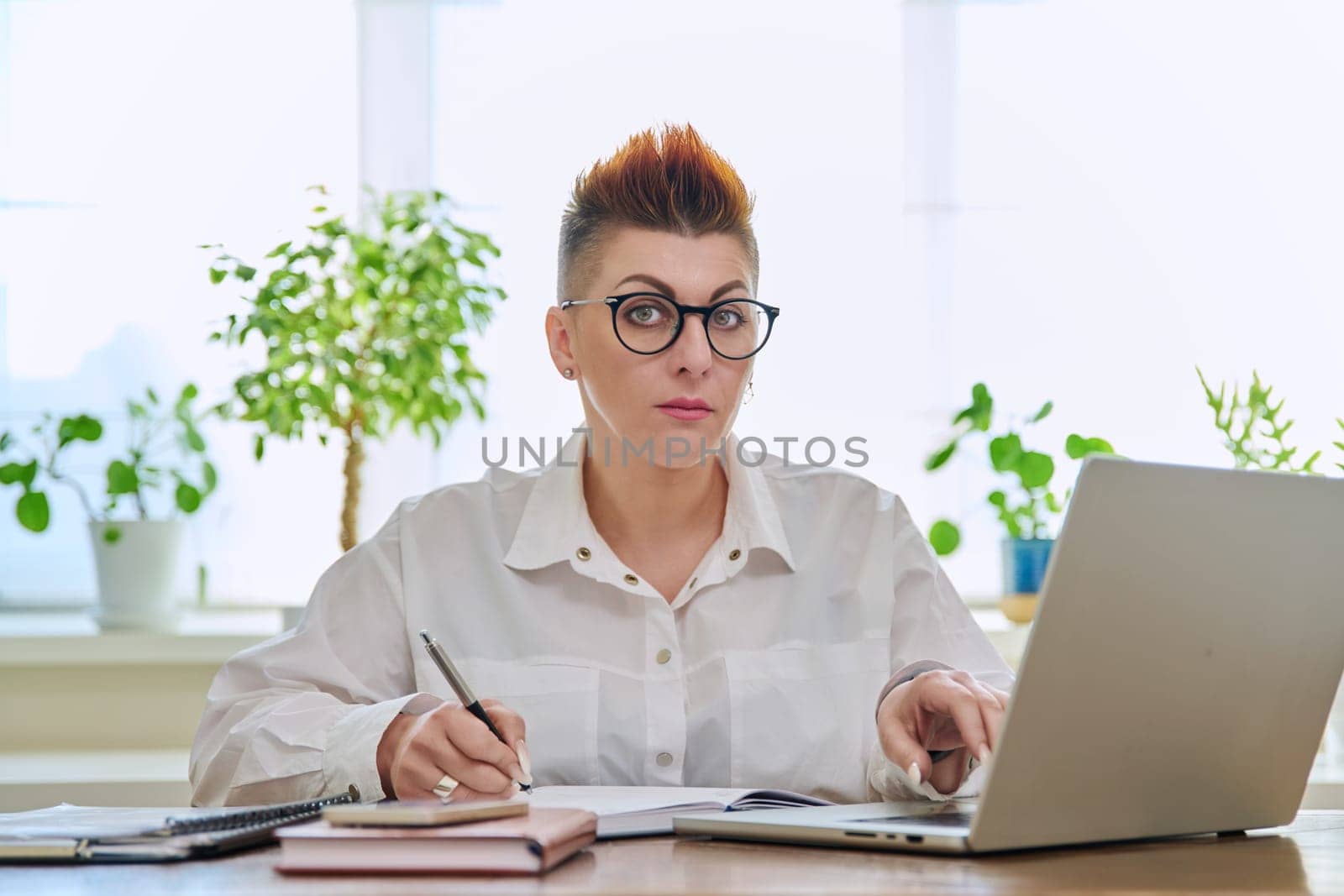 Portrait of mature woman working at home on computer laptop by VH-studio