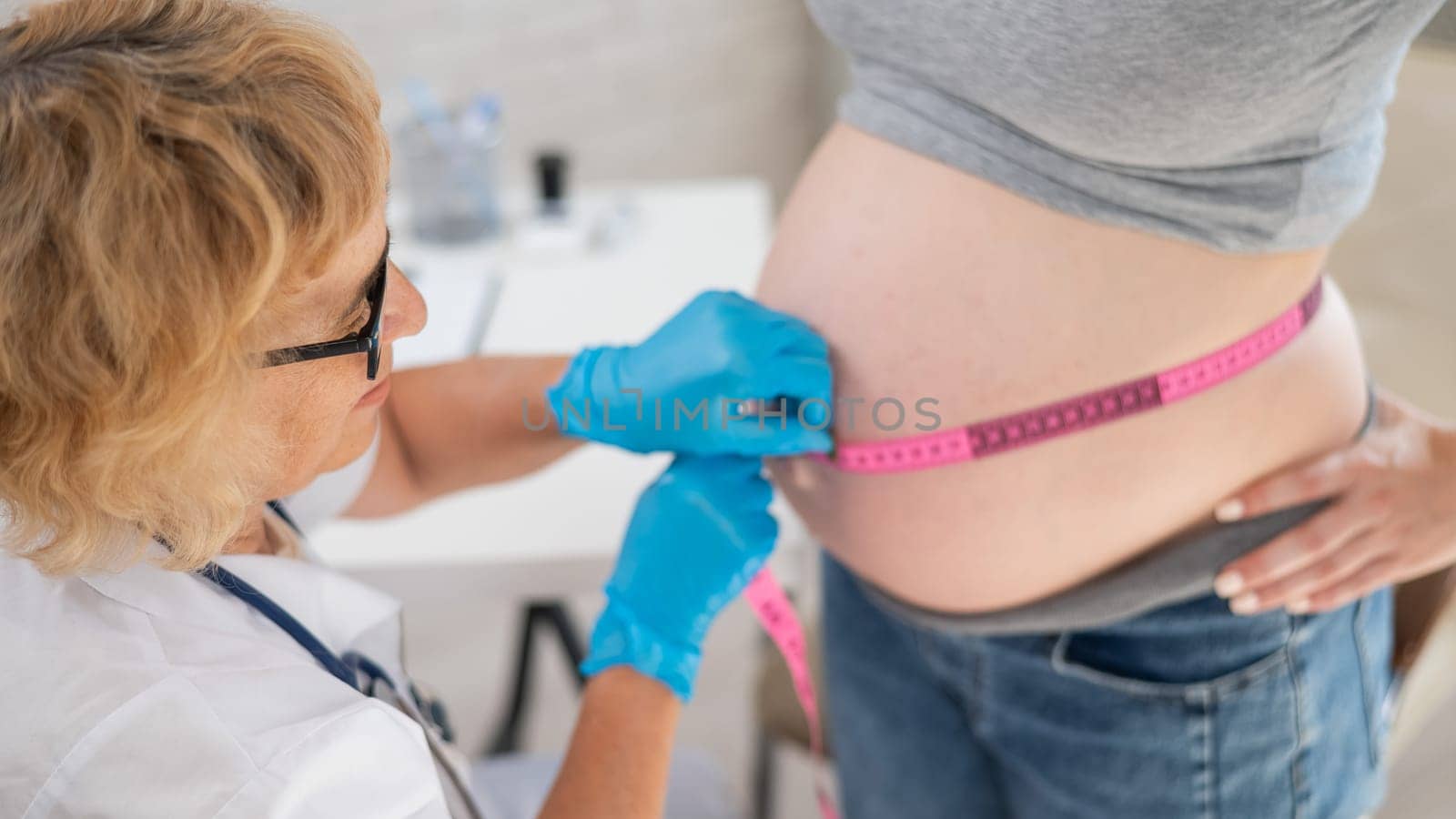 Doctor measuring the volume of a pregnant woman's abdomen using a centimeter tape