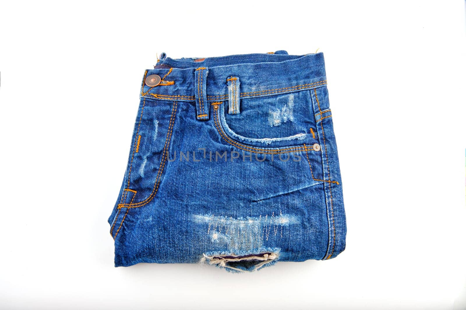 Denim trousers in blue with scuffs on the elements folded on a white background