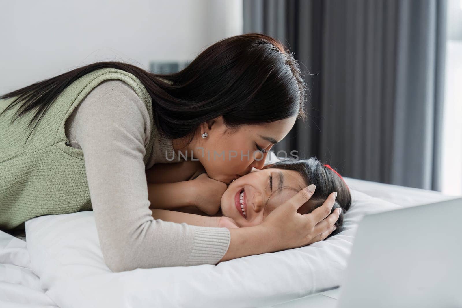 A woman is kissing a child on the head. The woman is wearing a green shirt