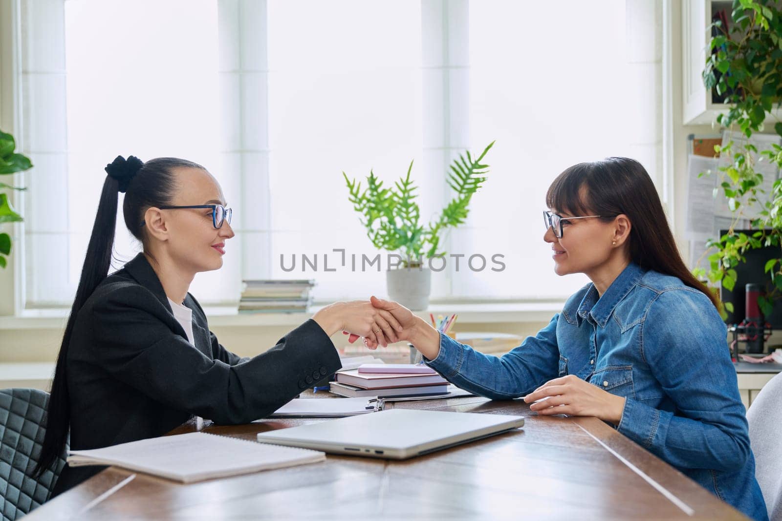 Mental therapy session of mature female with professional psychologist counselor. Talking women sitting at table, shaking hands sign greeting, psychology, psychotherapy, support help treatment concept