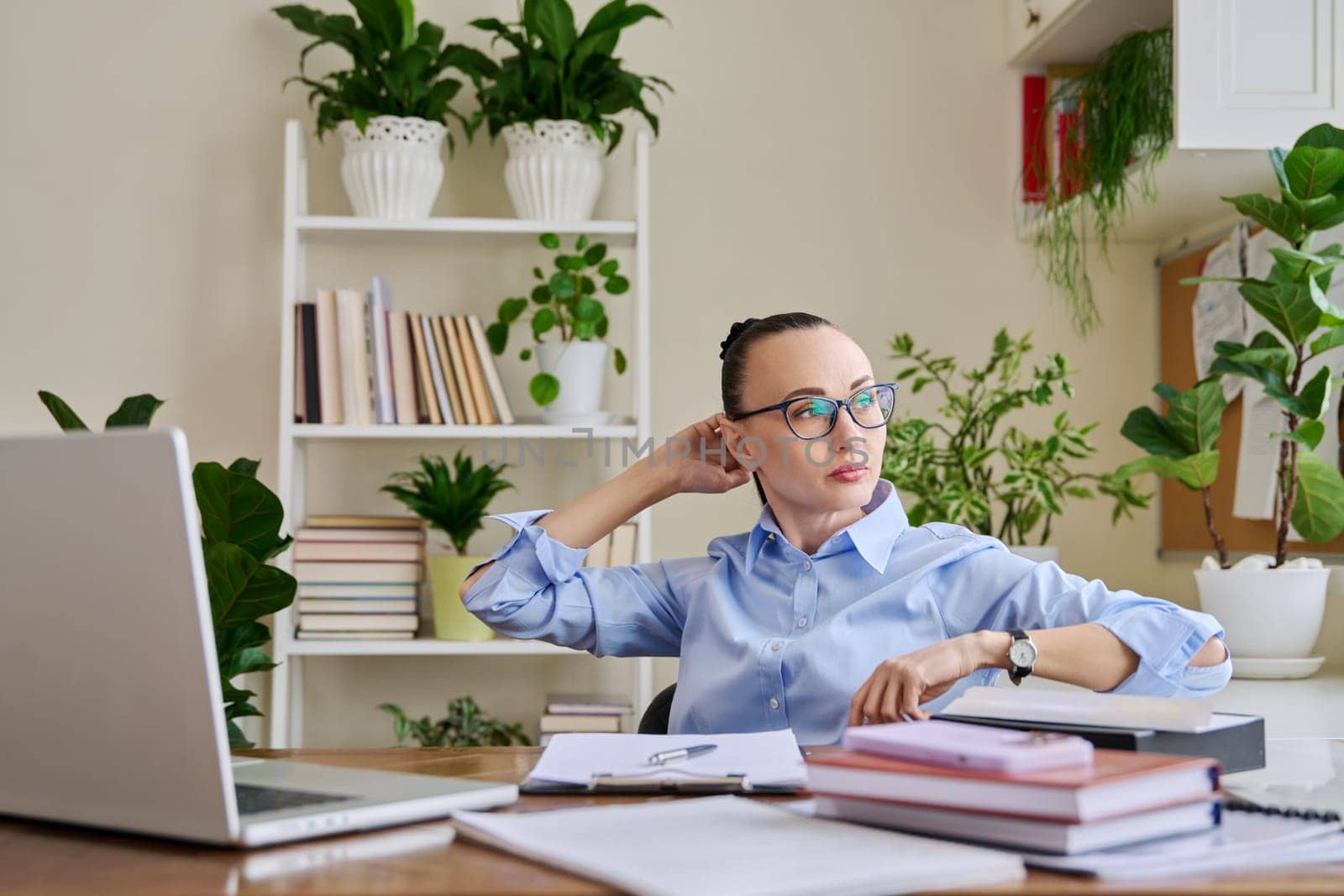 Calm relaxed business woman with her hands raised behind head in workplace, at desk with laptop computer. Tired satisfied female enjoying break, peace of mind, lack of stress