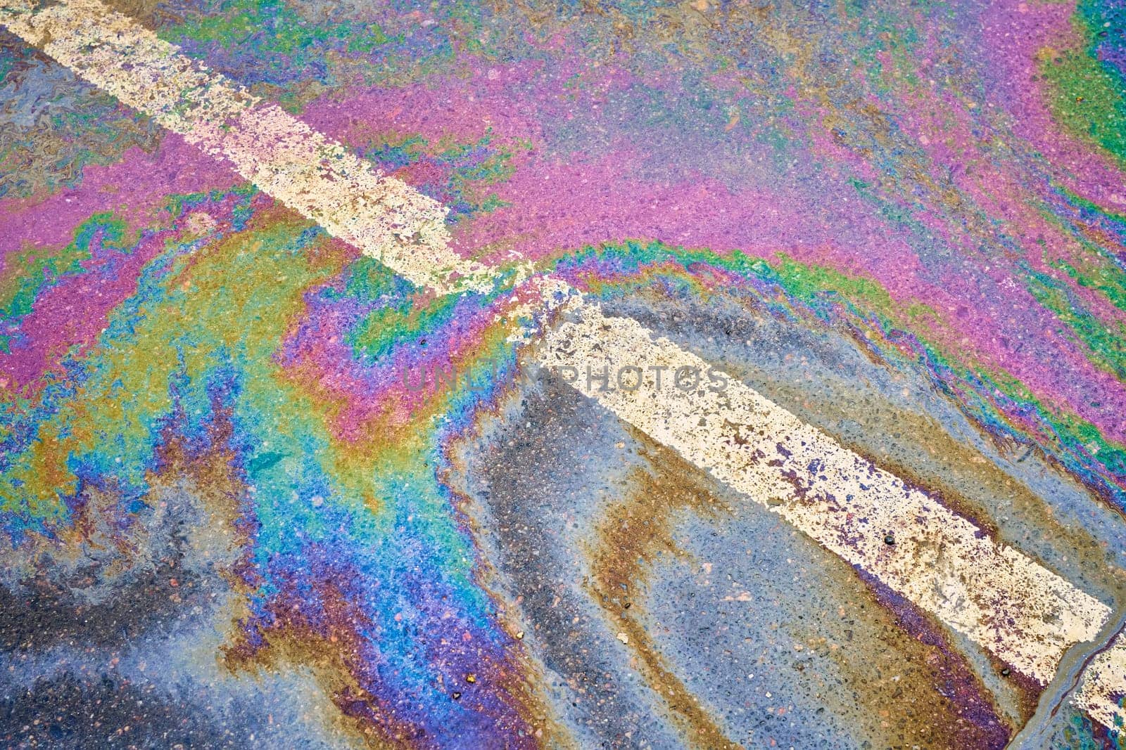 Wet asphalt affected by an oil spill, parking lot delineated by lines