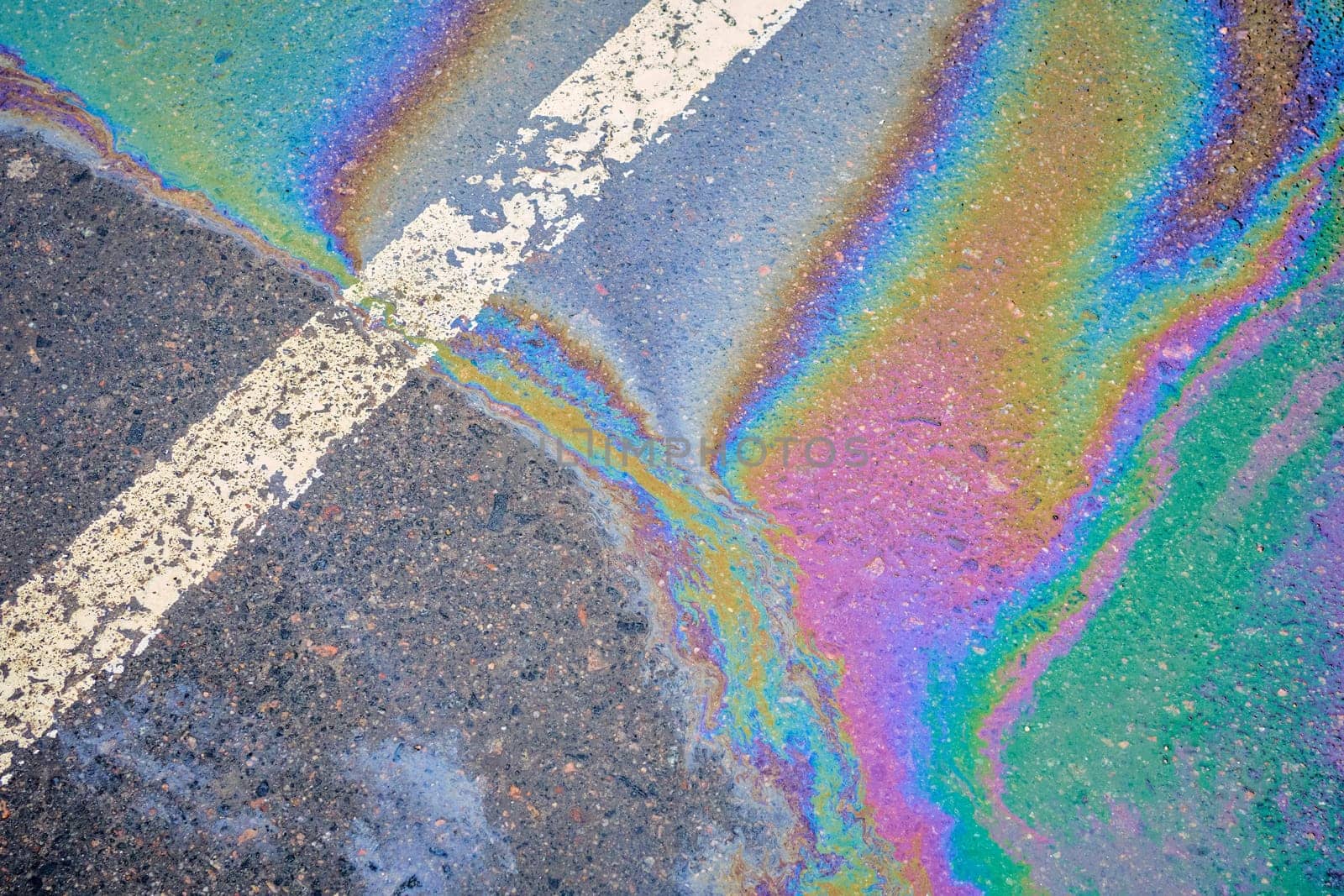 Oil spill on wet asphalt, parking lot with dividing lines. Highlighting environmental challenges related to water pollution