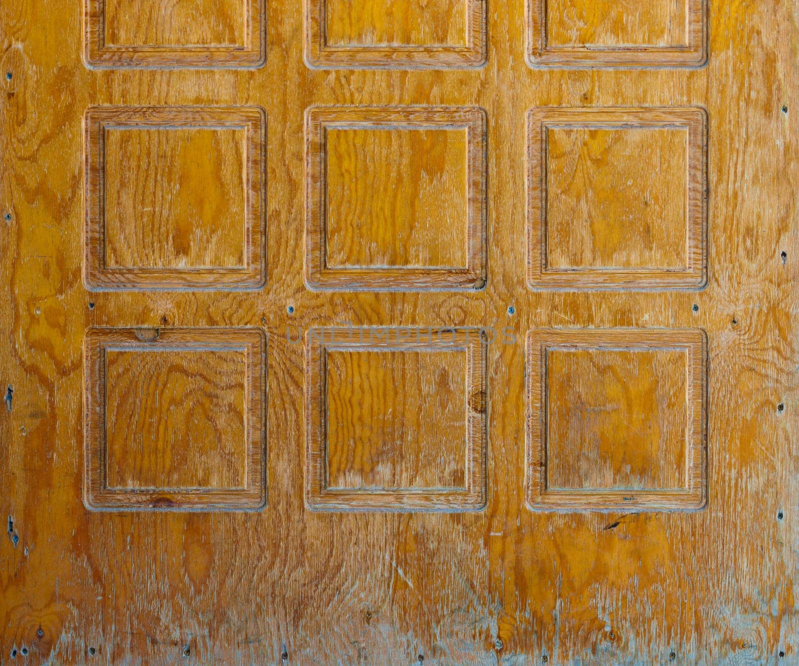 Brown plywood door texture with square decorative recessions carved into it
