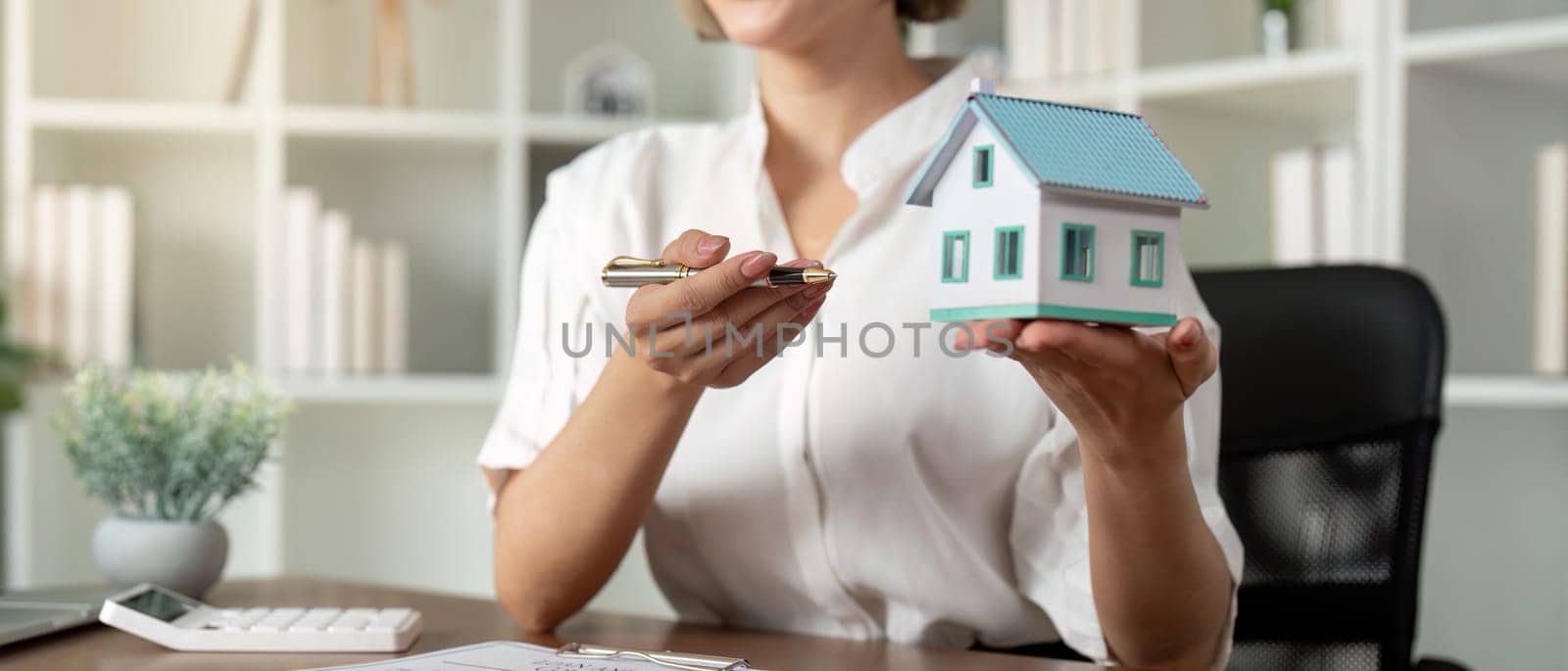 Home sale and home insurance concept, real estate agent with house model talking to client about buy home insurance and client signing contract under formal contract agreement by nateemee