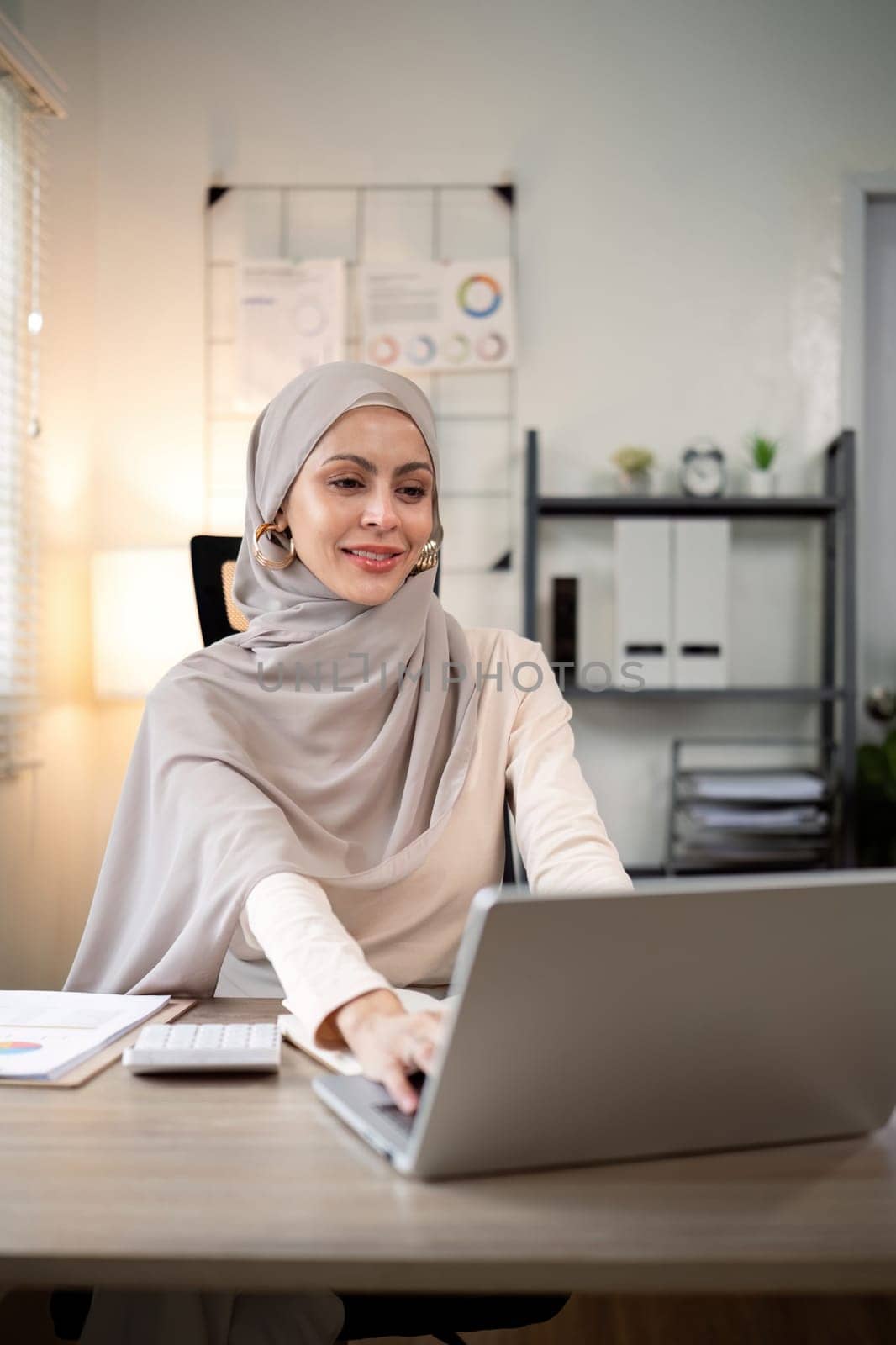 Asian Muslim businesswoman in hijab head scarf working with paper document in the modern office. diversity and office concept.