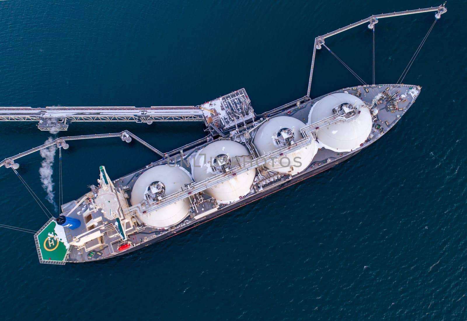 Aerial of Liquified Natural Gas LNG carrier moored to a small gas terminal. Fuel crisis. Sanctions. Top down shot.