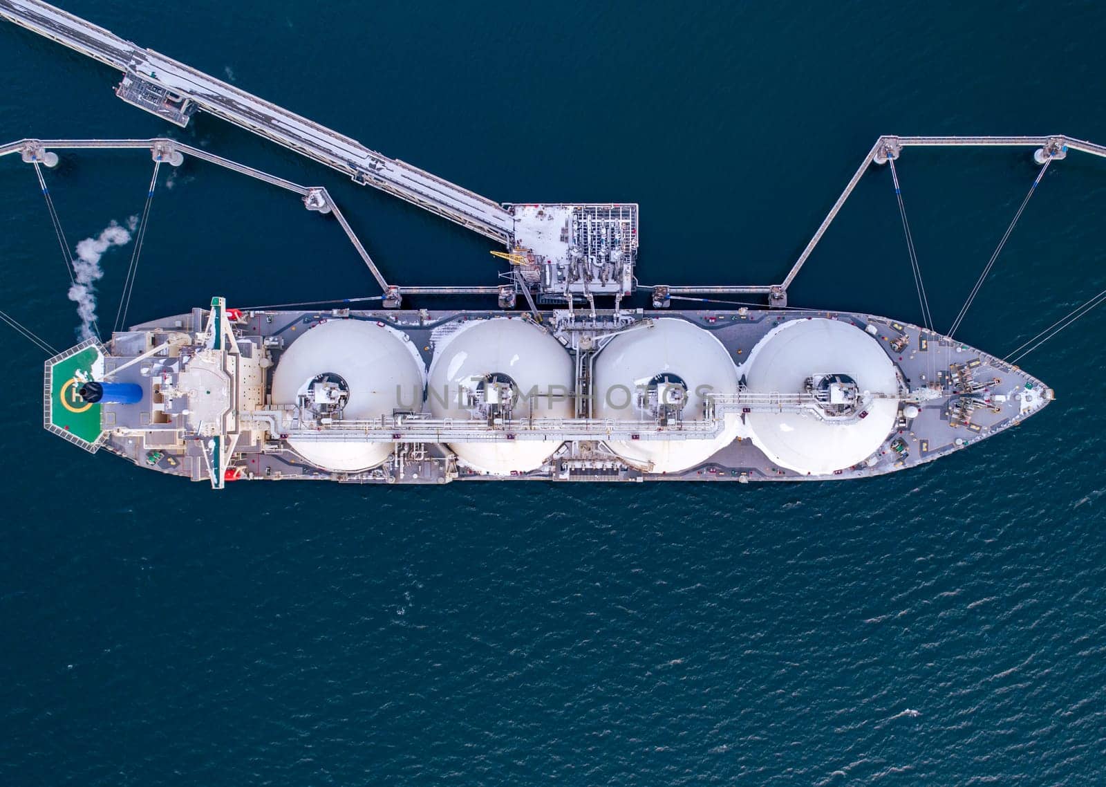 Aerial of Liquified Natural Gas LNG carrier moored to a small gas terminal. Fuel crisis. Sanctions. Top down shot.