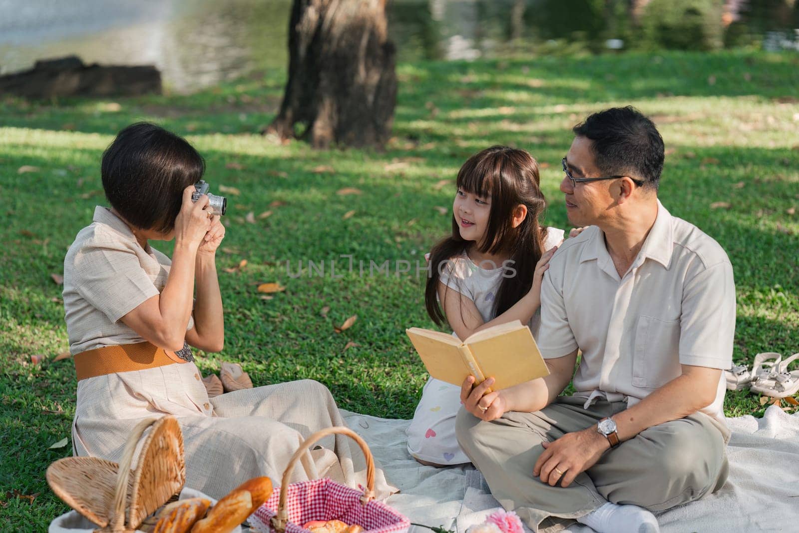 Family day, family picnic together at the park. Retired grandparent take granddaughter to relax and spend time together at the park.