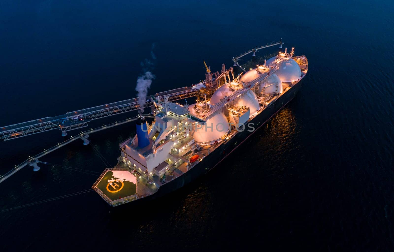 Aerial of Liquified Natural Gas LNG carrier moored to a small gas terminal at dusk. Fuel crisis. Sanctions by Busker