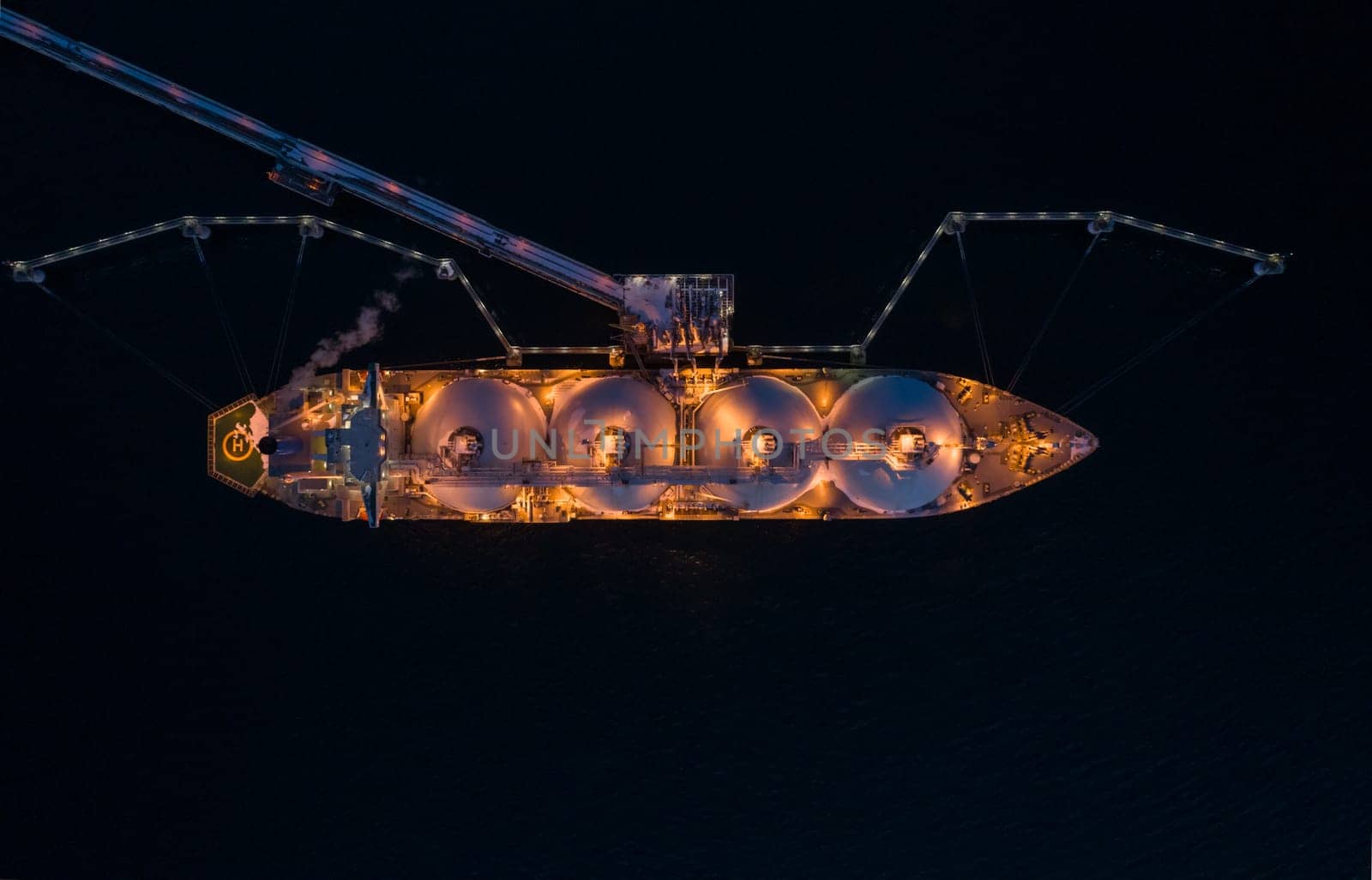 Aerial of Liquified Natural Gas LNG carrier moored to a small gas terminal at night. Fuel crisis. Sanctions. by Busker