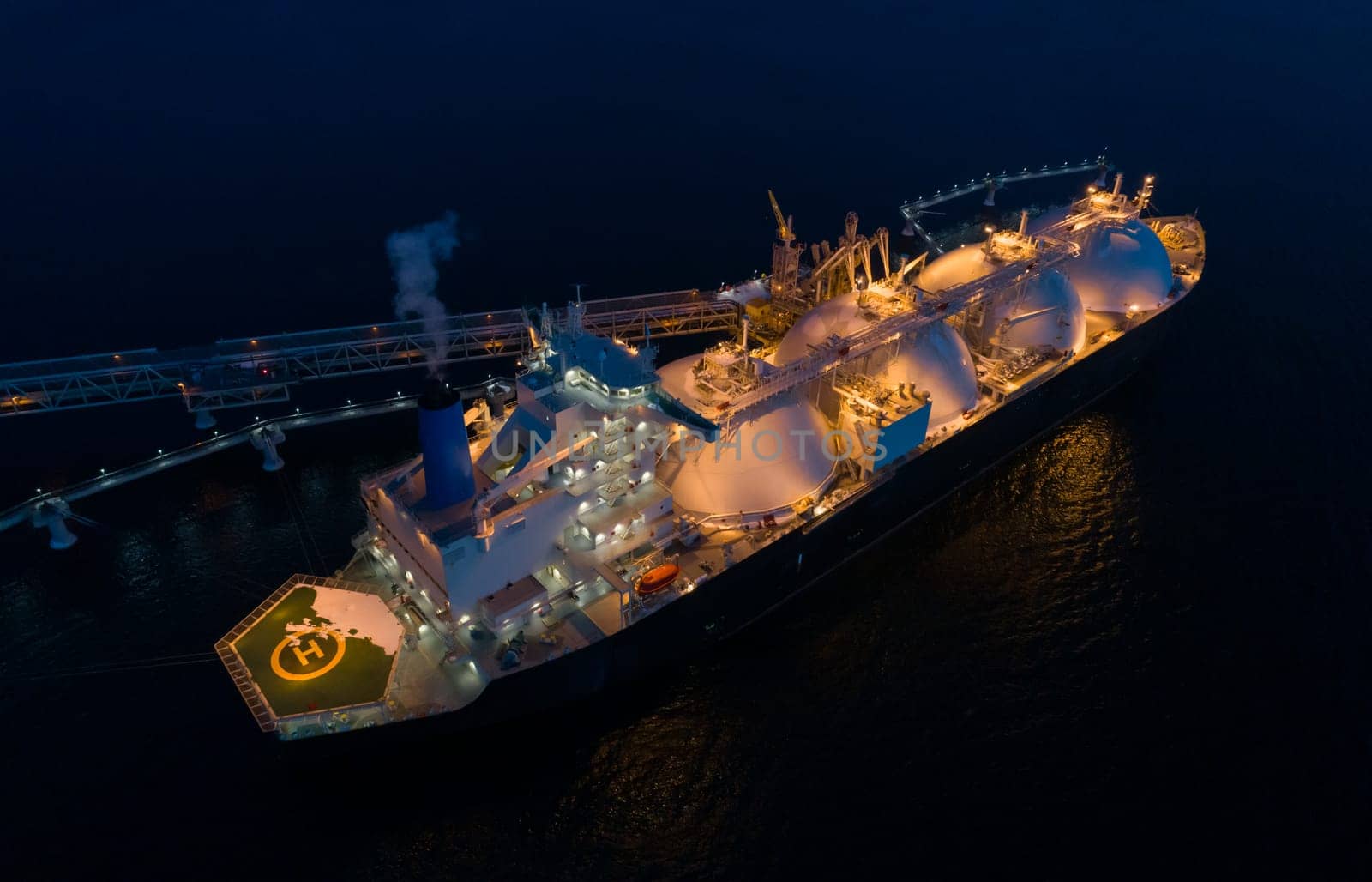 Aerial of Liquified Natural Gas LNG carrier moored to a small gas terminal at dusk. Fuel crisis. Sanctions by Busker