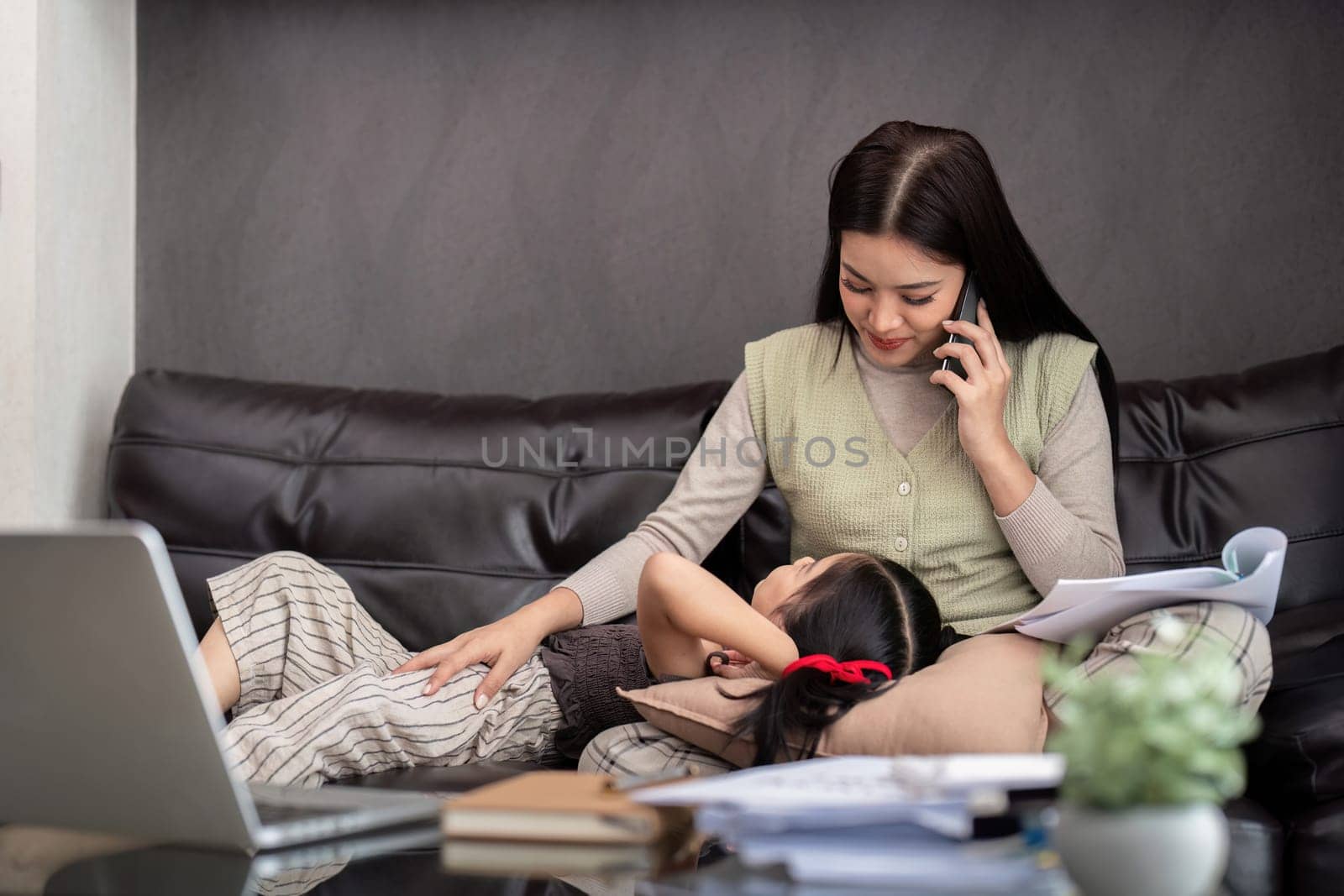 Business woman or mom working with her little daughter at a laptop. Freelance, work from home.