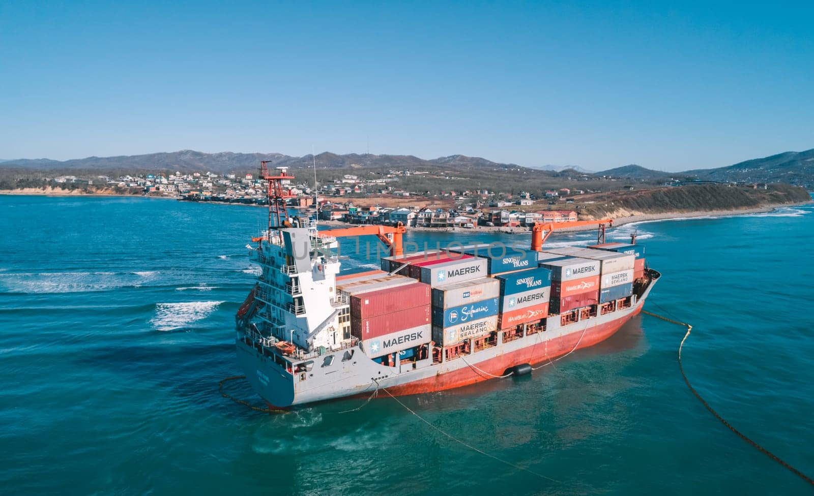 Aerial view of a RISE SHINE container cargo ship stands aground after a storm with floating boom around the ship to prevent the spread of petroleum. Container ship ran aground during the storm.