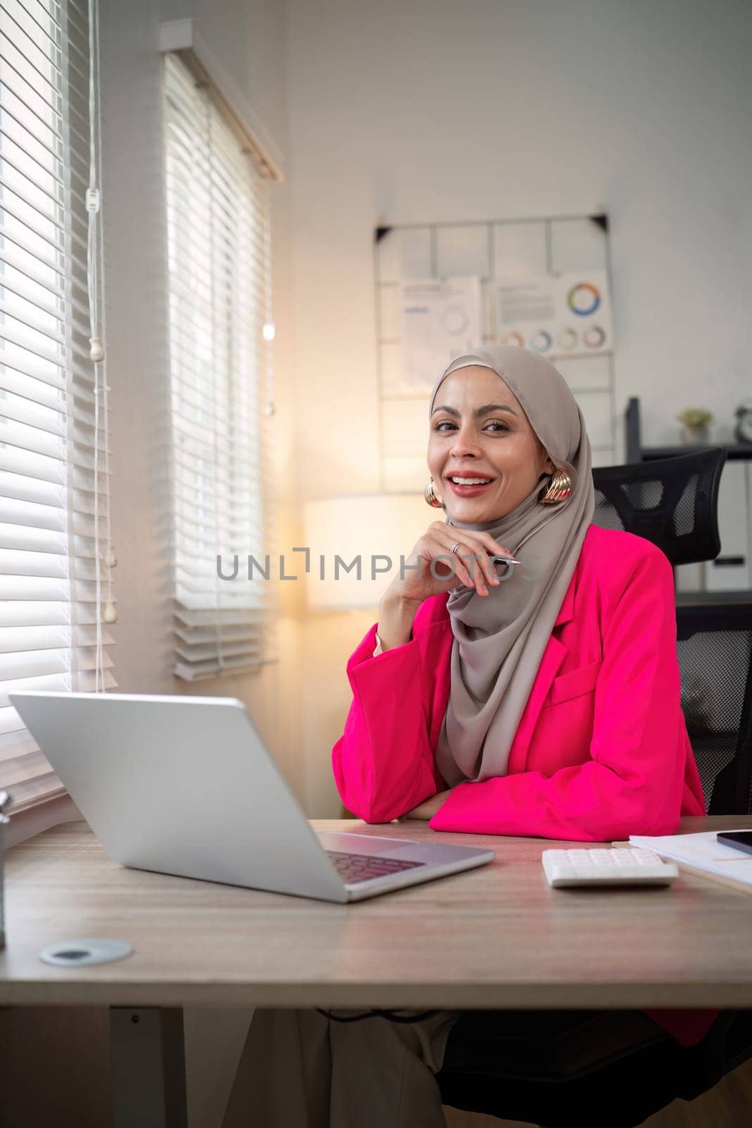 Muslim business woman hijab working about financial with business report and calculator on laptop in home office by nateemee