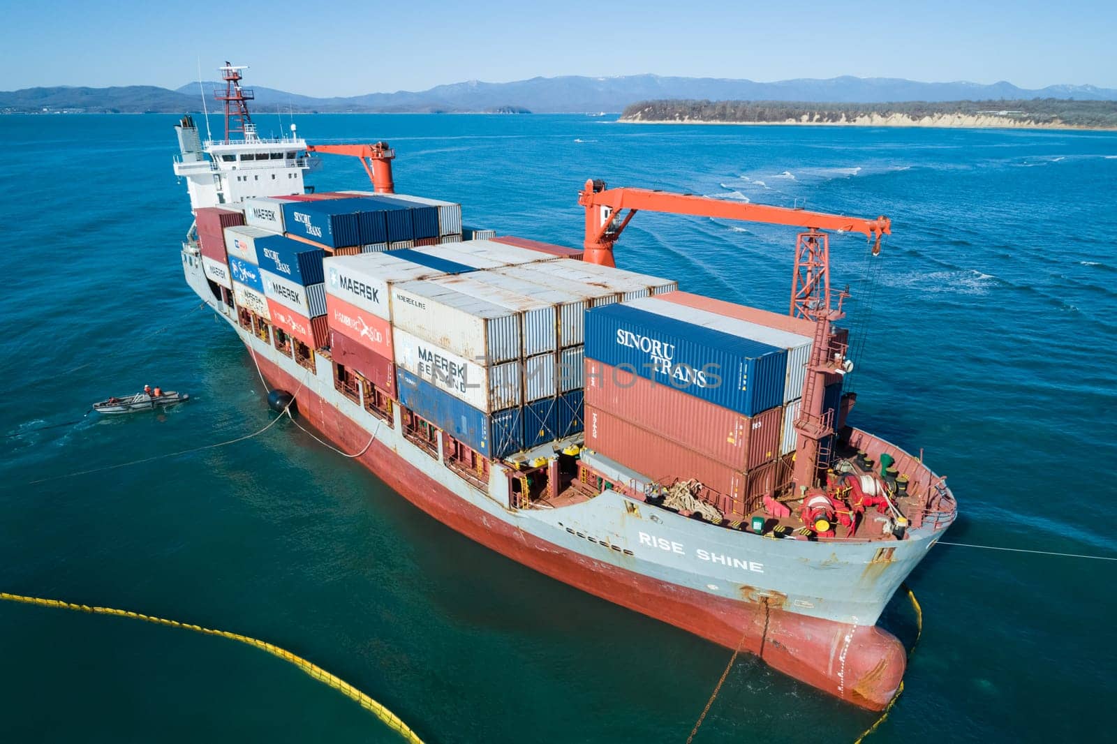 Aerial view of a RISE SHINE container cargo ship stands aground after a storm with floating boom around the ship to prevent the spread of petroleum. Container ship ran aground during the storm.