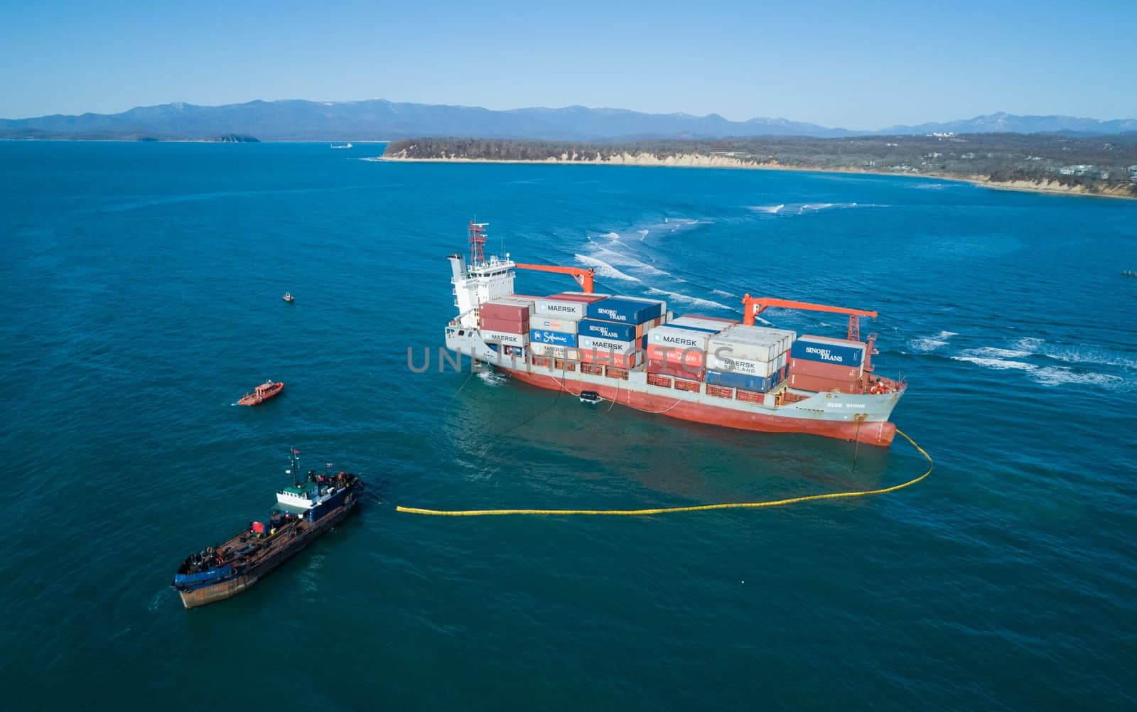 Aerial view of a RISE SHINE container cargo ship stands aground after a storm with floating boom around the ship to prevent the spread of petroleum. Container ship ran aground during the storm.