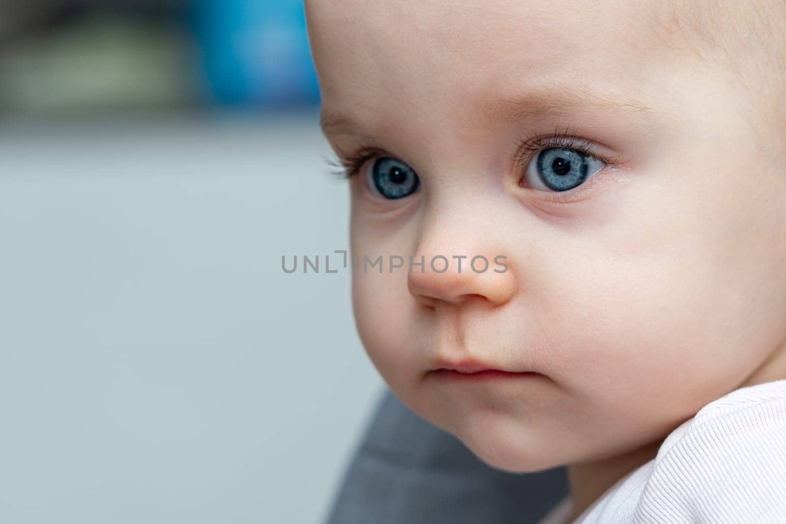 One year old baby gazes to the side with curious eyes. Concept of innocence and wonder in childhood by Mariakray