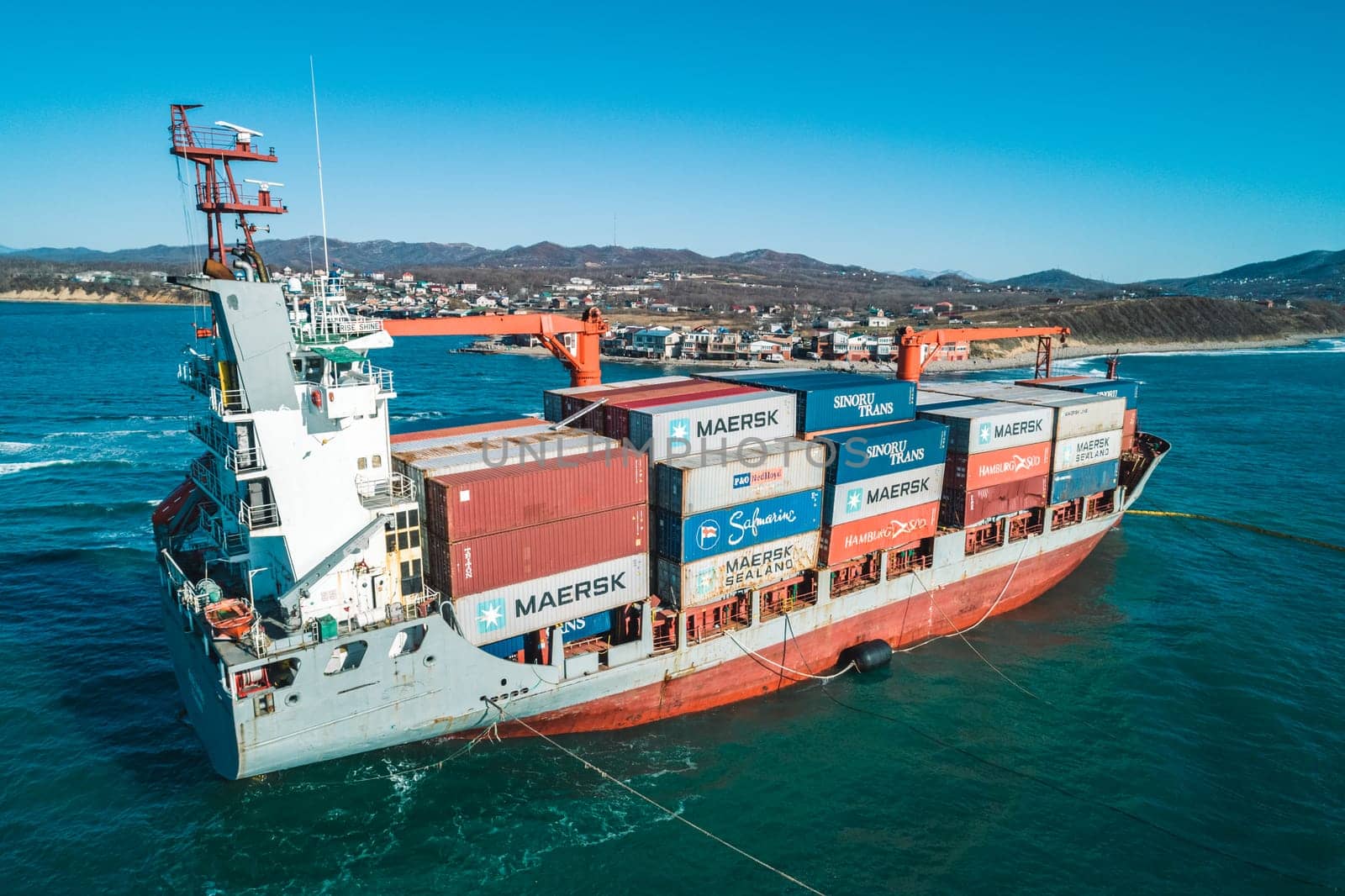 Aerial view of a RISE SHINE container cargo ship stands aground after a storm with floating boom around the ship to prevent the spread of petroleum. Container ship ran aground during the storm.