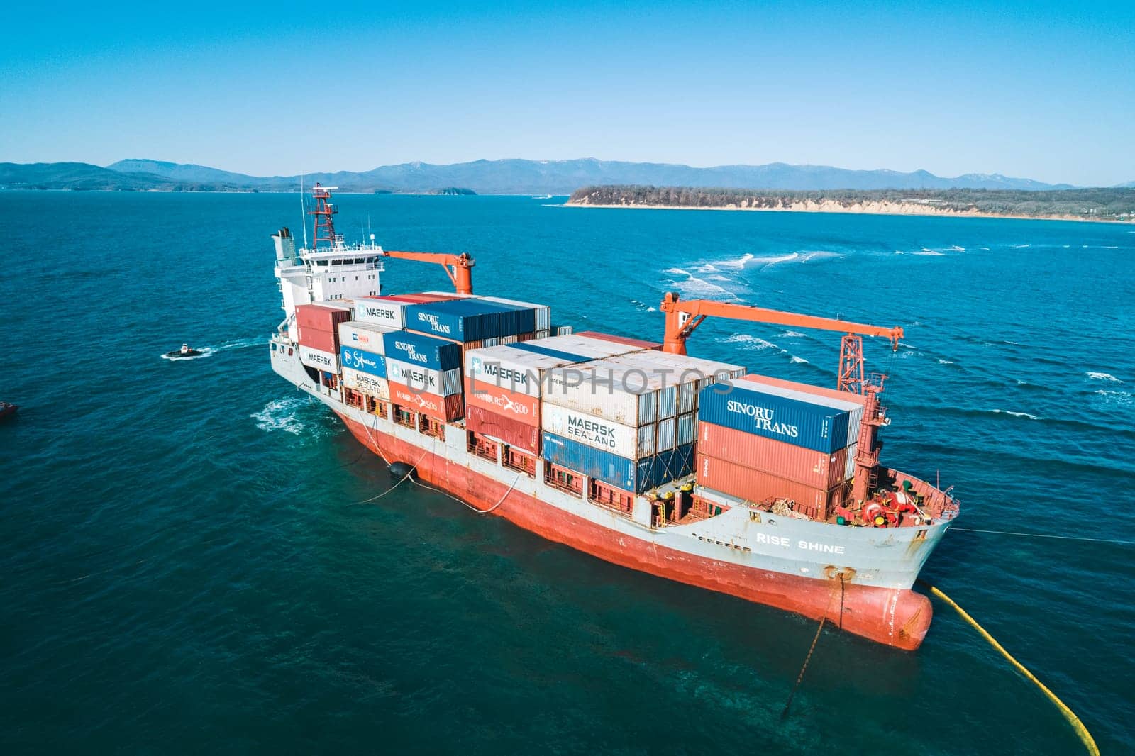 Aerial view of a RISE SHINE container cargo ship stands aground after a storm with floating boom around the ship to prevent the spread of petroleum. Container ship ran aground during the storm.