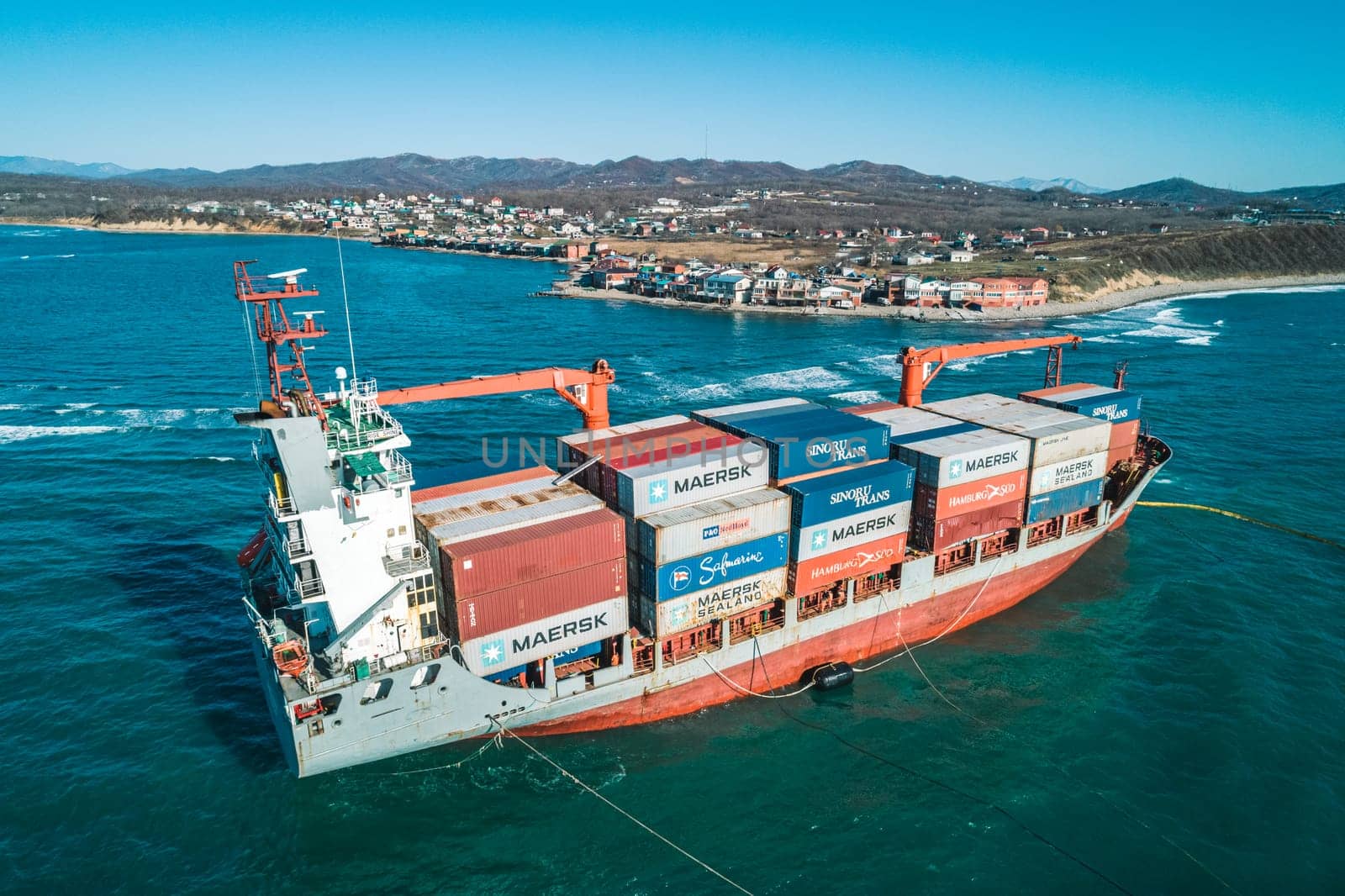 Aerial view of a RISE SHINE container cargo ship stands aground after a storm with floating boom around the ship to prevent the spread of petroleum. Container ship ran aground during the storm.