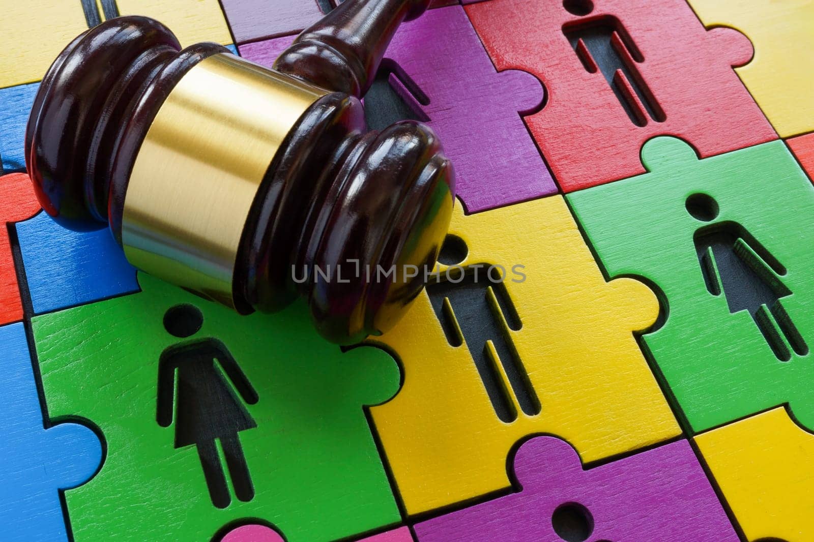 A puzzle of male and female figures as a symbol of diversity and equality and a gavel as concept of law.