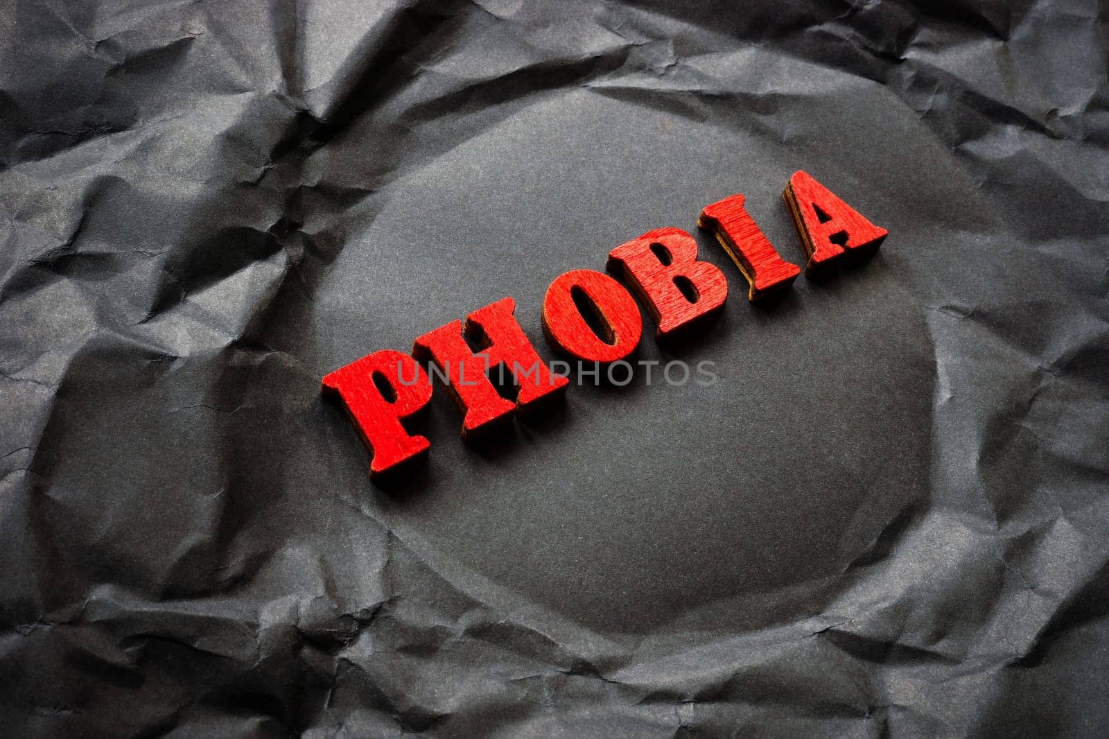 Black crumpled paper with the word phobia. by designer491