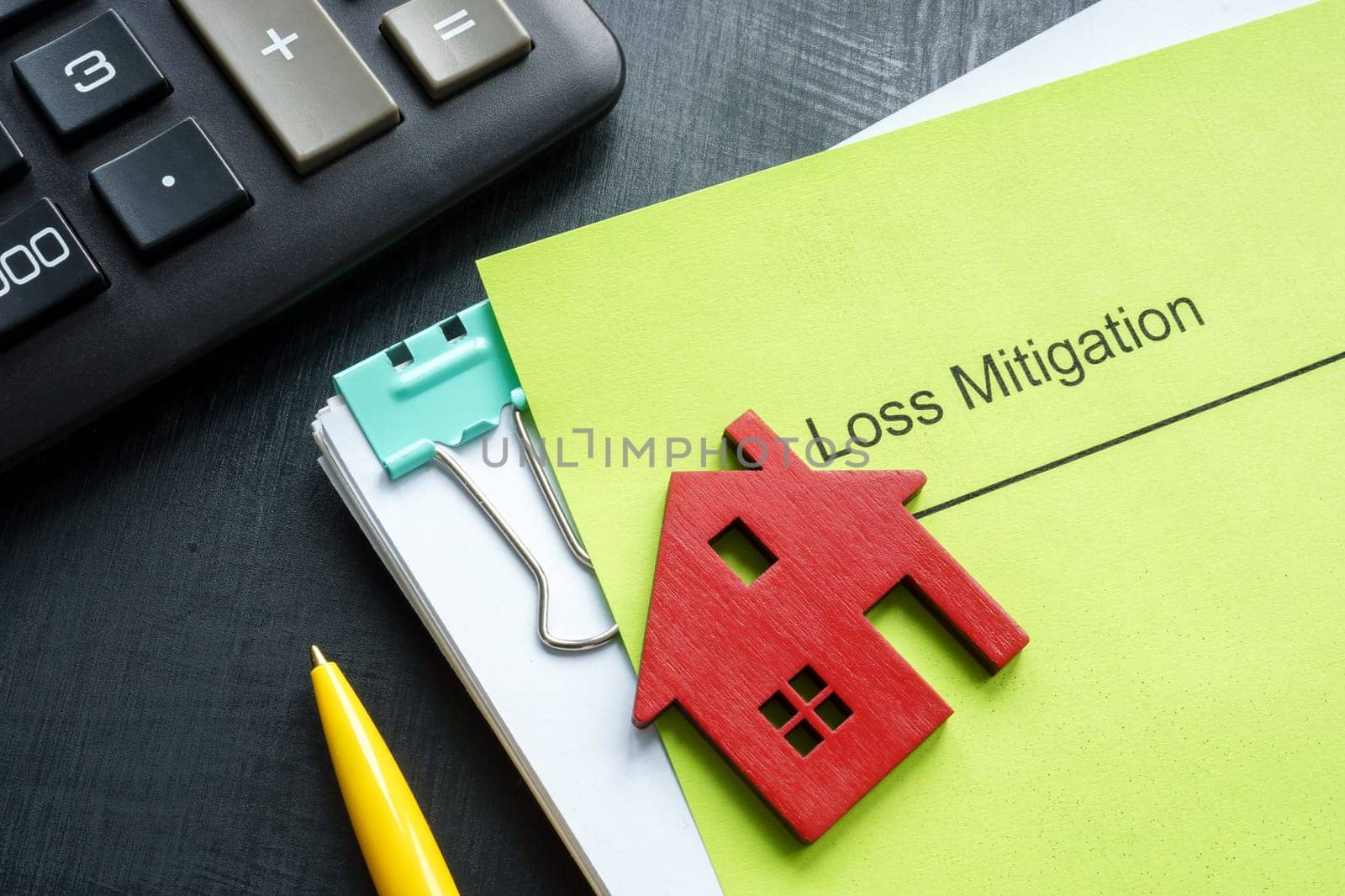 A stack of documents about loss mitigation with a figurine of a house. by designer491