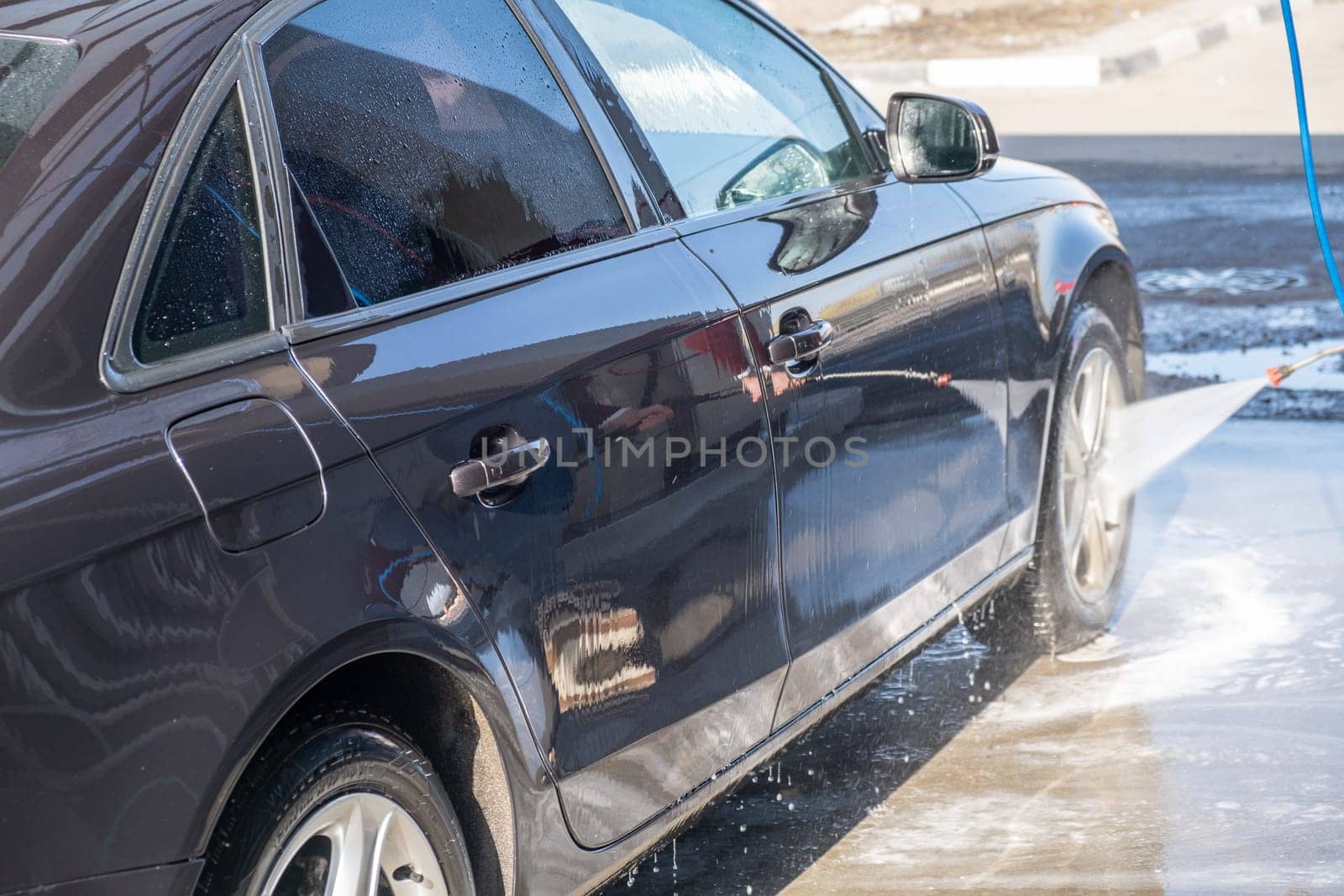 A man washes off the foam while washing the car. by AnatoliiFoto