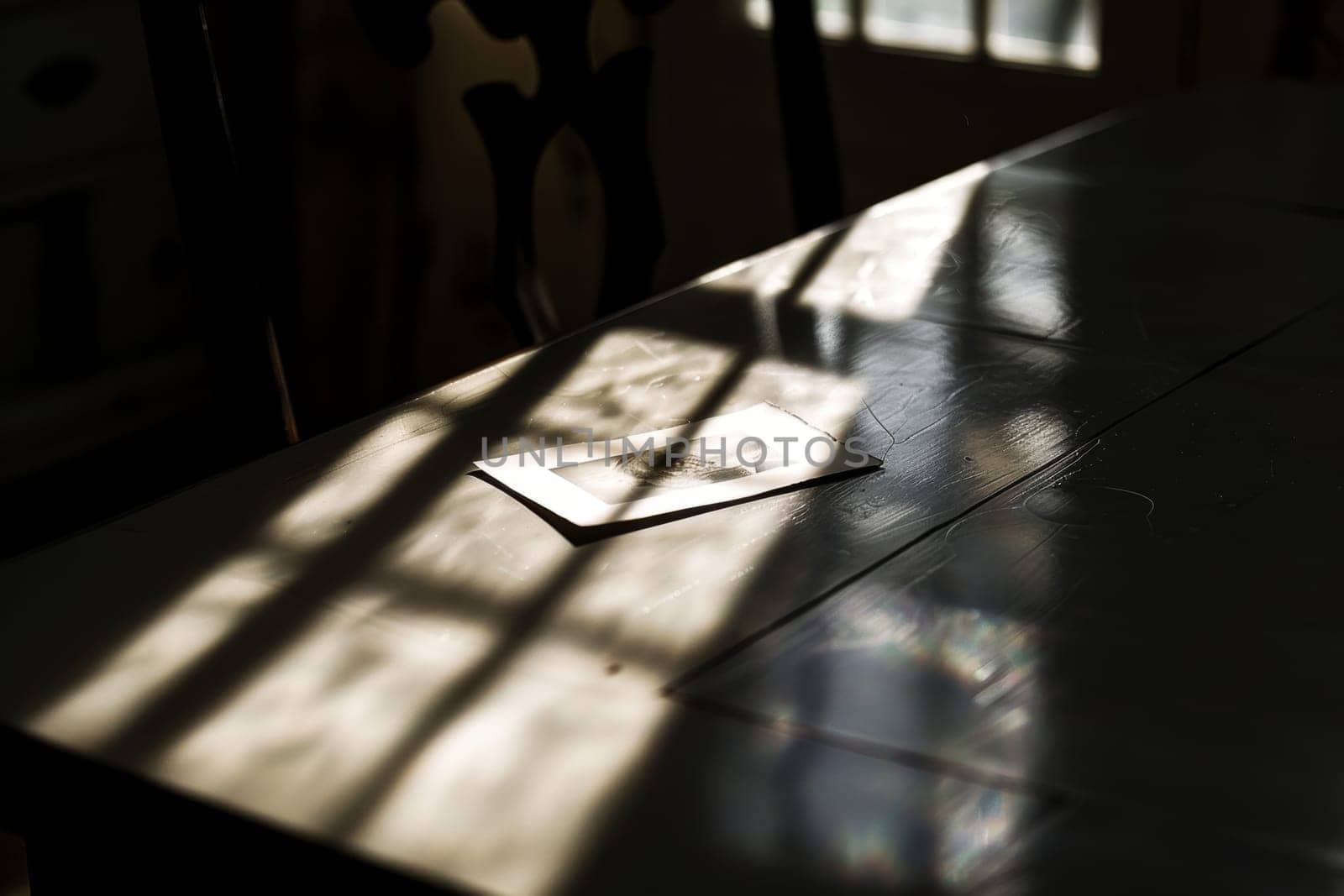 An evocative scene where a solitary photograph lies on a table, bathed in sunlight that casts dramatic shadows, invoking nostalgia and reflection.
