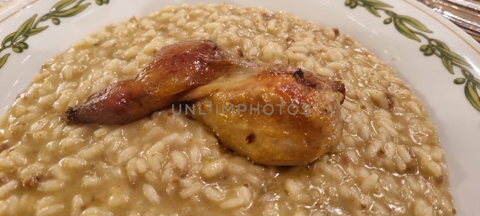 Close-up of creamy risotto with a succulent roasted chicken leg on a decorative plate