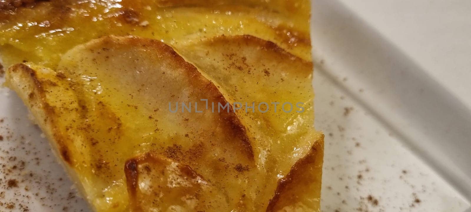 Detailed image capturing the texture and glaze of a freshly baked apple tart piece sprinkled with cinnamon