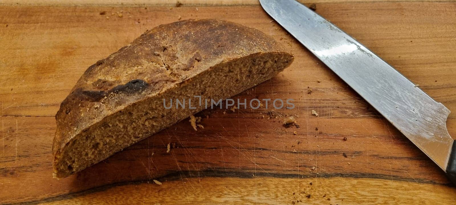 Close-up of a rustic artisan bread loaf sliced on a wooden cutting board next to a knife