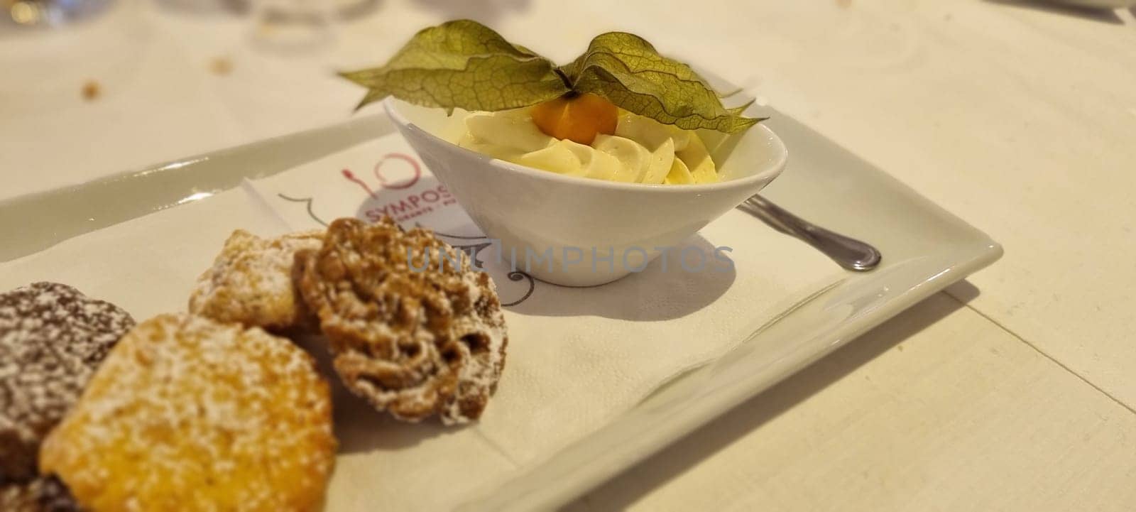 Delicate selection of italian pastries served with whipped cream garnished with a physalis fruit