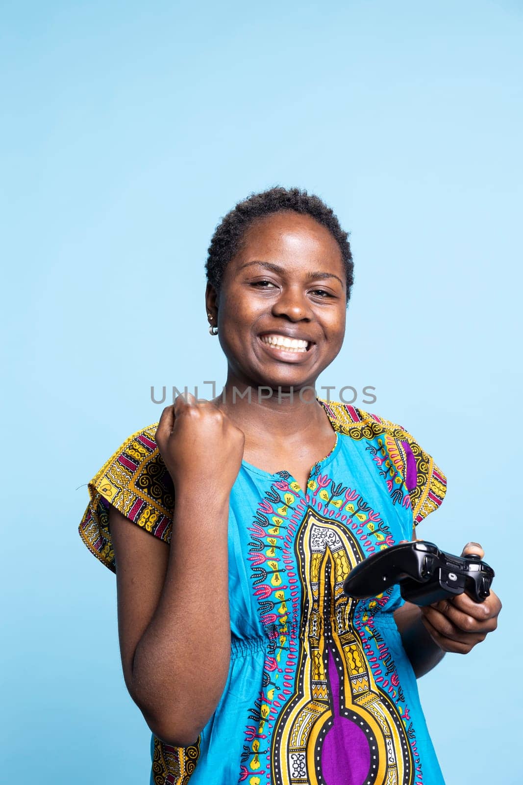African american smiling person winning videogames competition on camera, enjoying gaming tournament victory and playing with a controller. Positive girl being pleased with her online success.