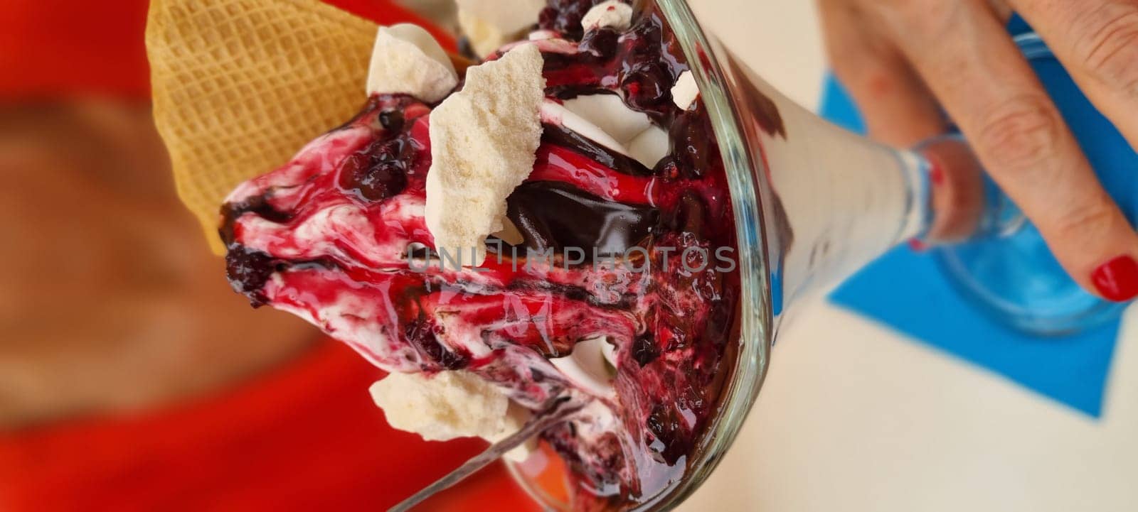 Close-up of a berry sundae with ice cream and waffle cone in a glass