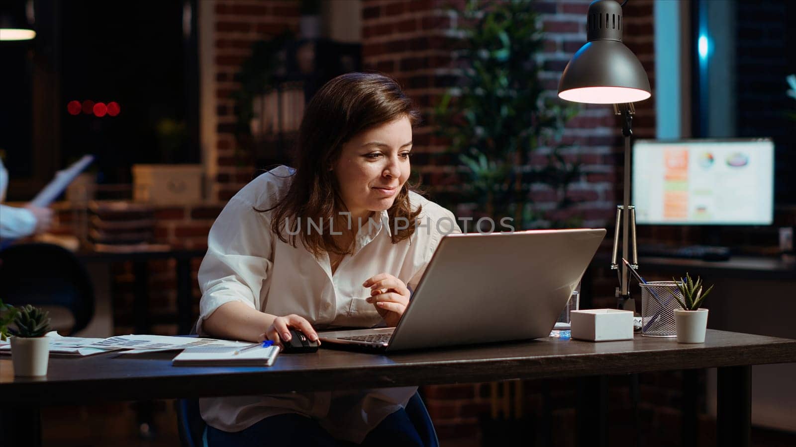 Woman in office at night celebrating finalizing deal with business partners by DCStudio