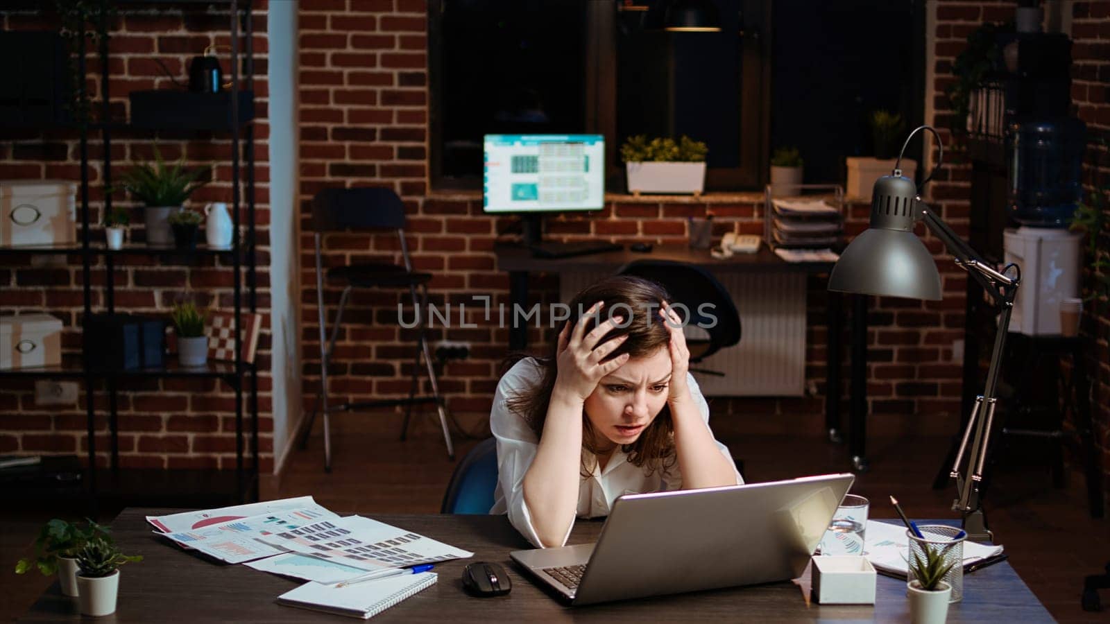 Businesswoman working on company project overnight, feeling frustrated, putting head in hands. Upset employee sighing while looking over figures on laptop screen, exasperated by failure